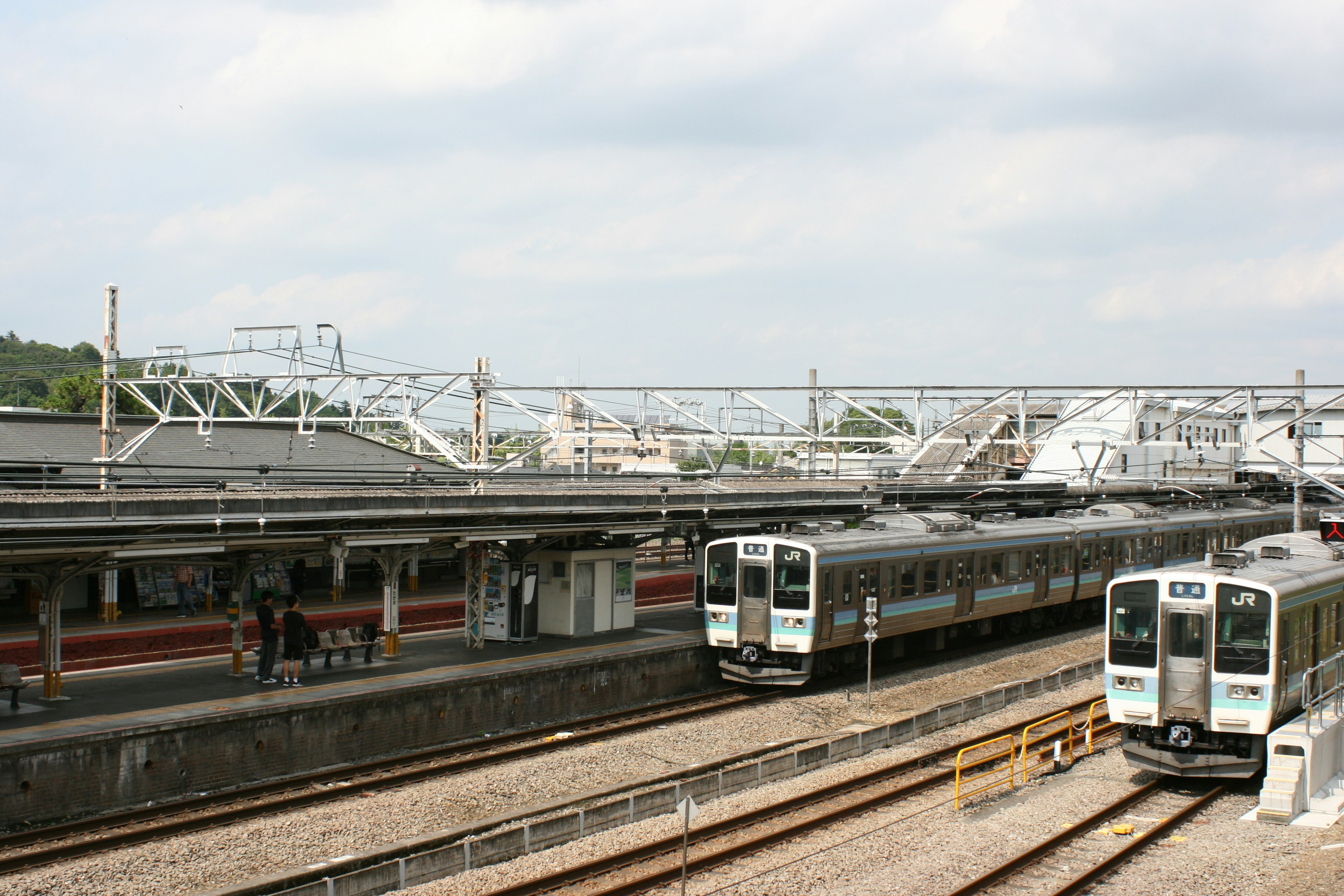 Two trains at a railway station with visible structures and tracks