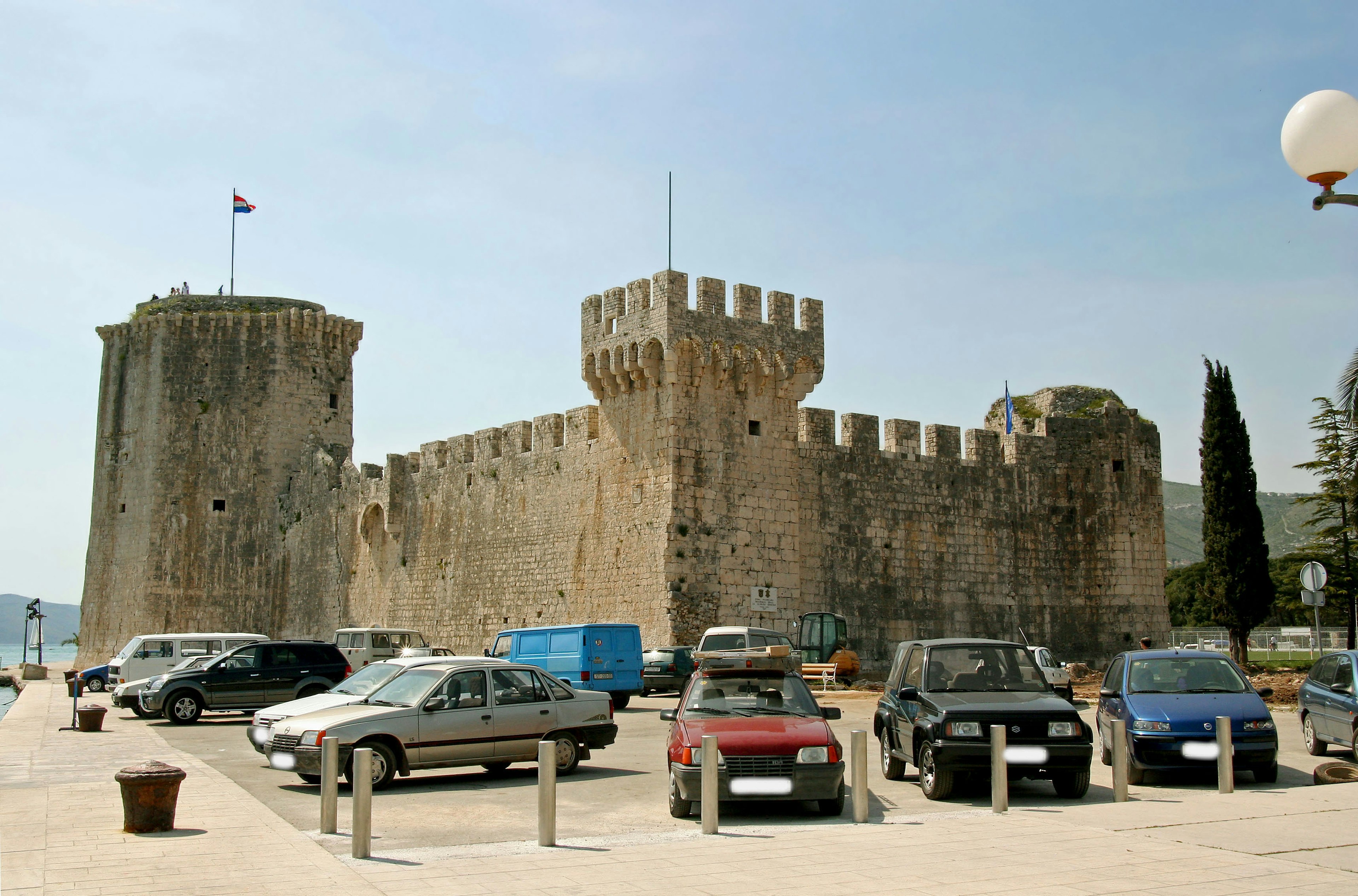 Castillo medieval con muros de piedra y coches estacionados