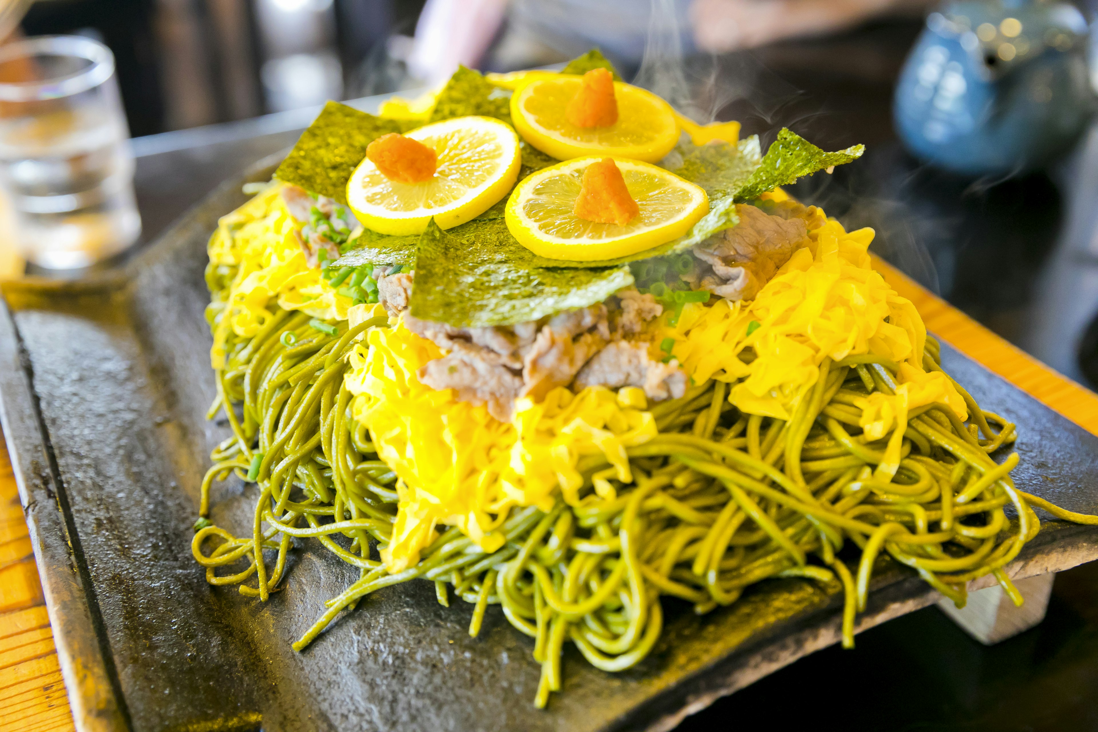 Un piatto vivace di noodle verdi guarnito con fette di limone e alga