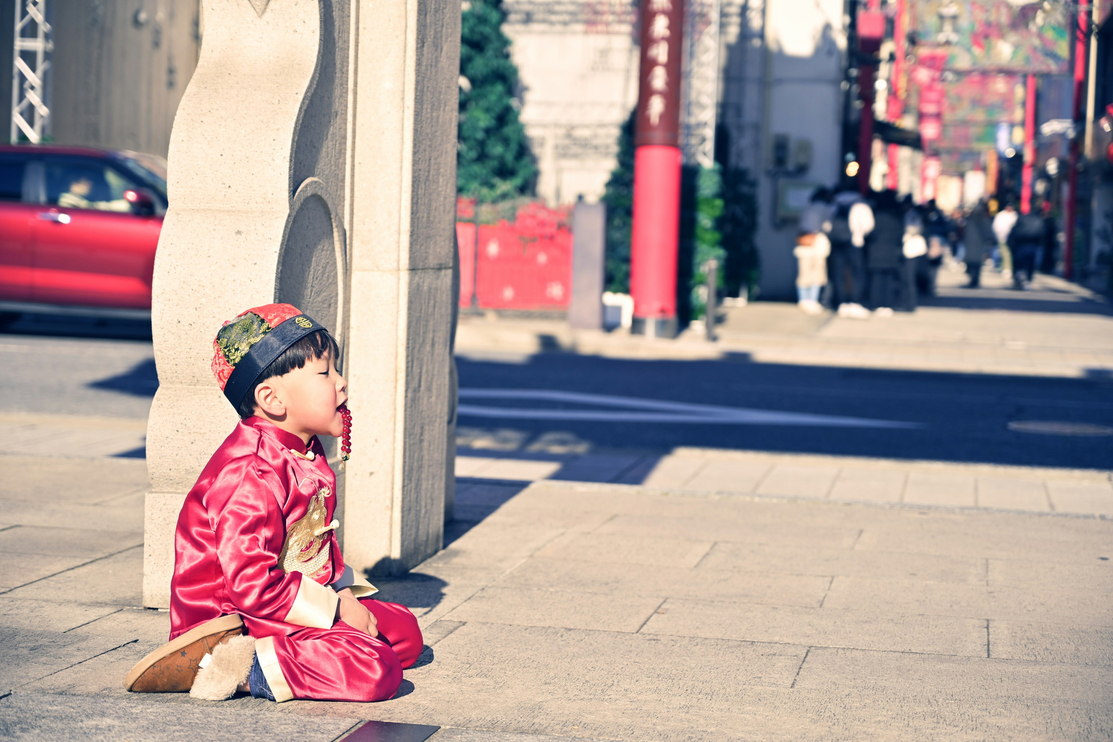 Un niño con un traje rojo sentado en la esquina de la calle