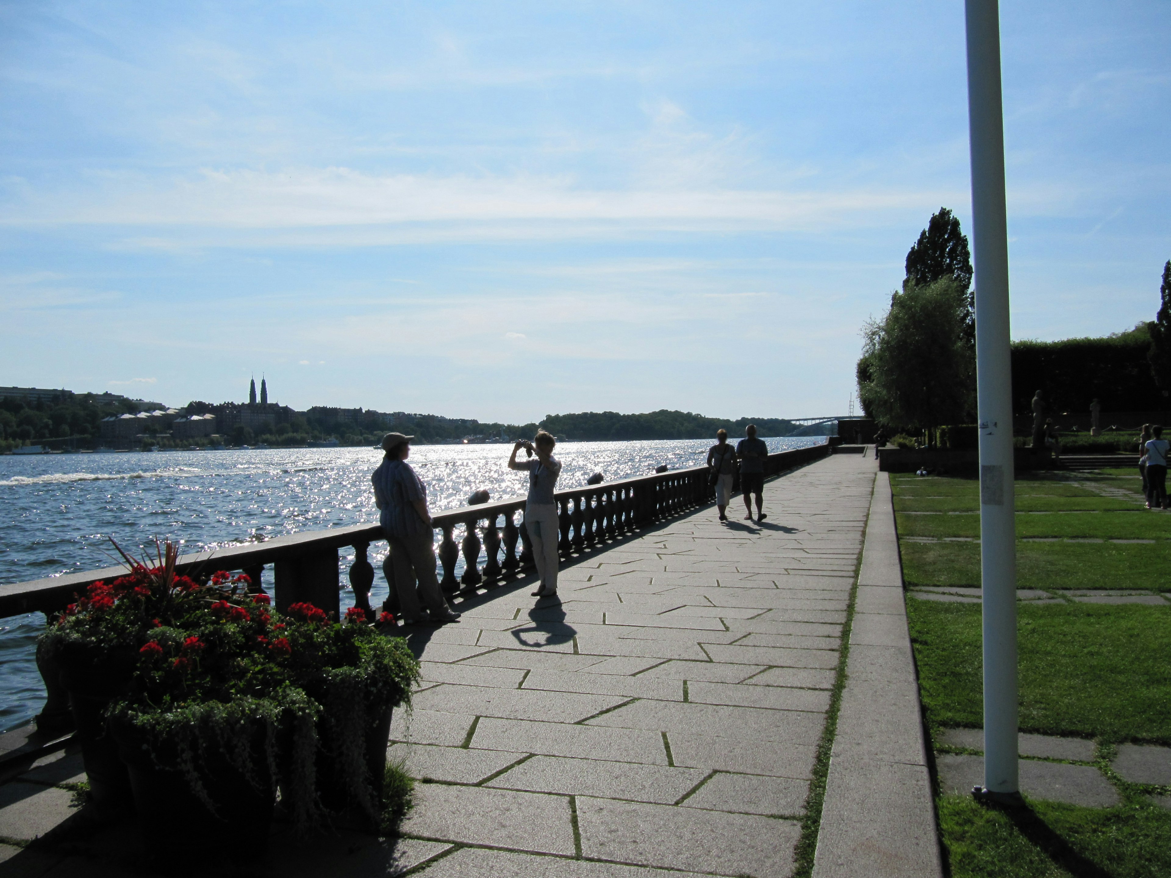 Promenade panoramica sul lungomare con persone che passeggiano e vasi di fiori