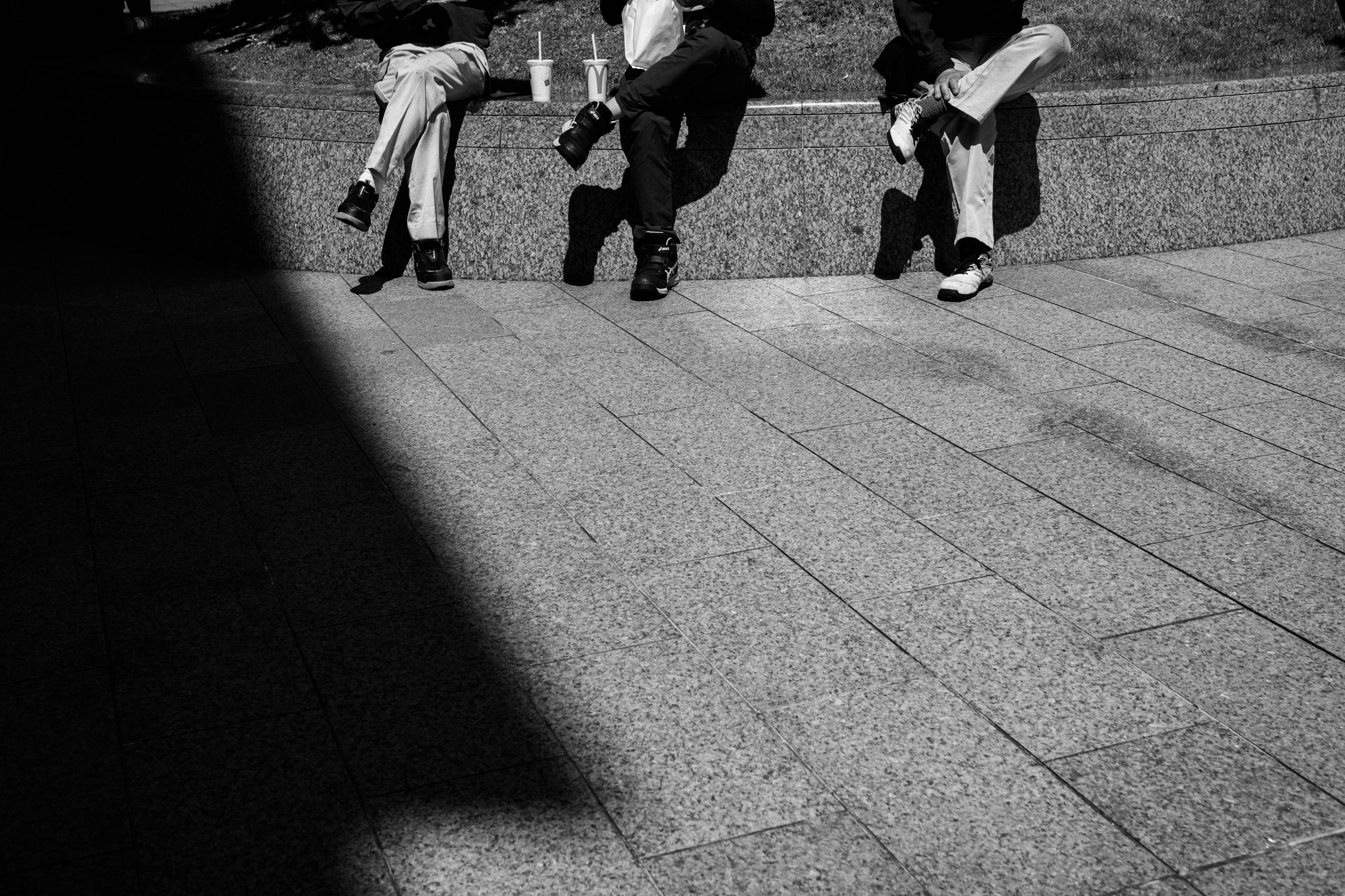 Photo en noir et blanc montrant trois personnes assises sur une surface en pierre