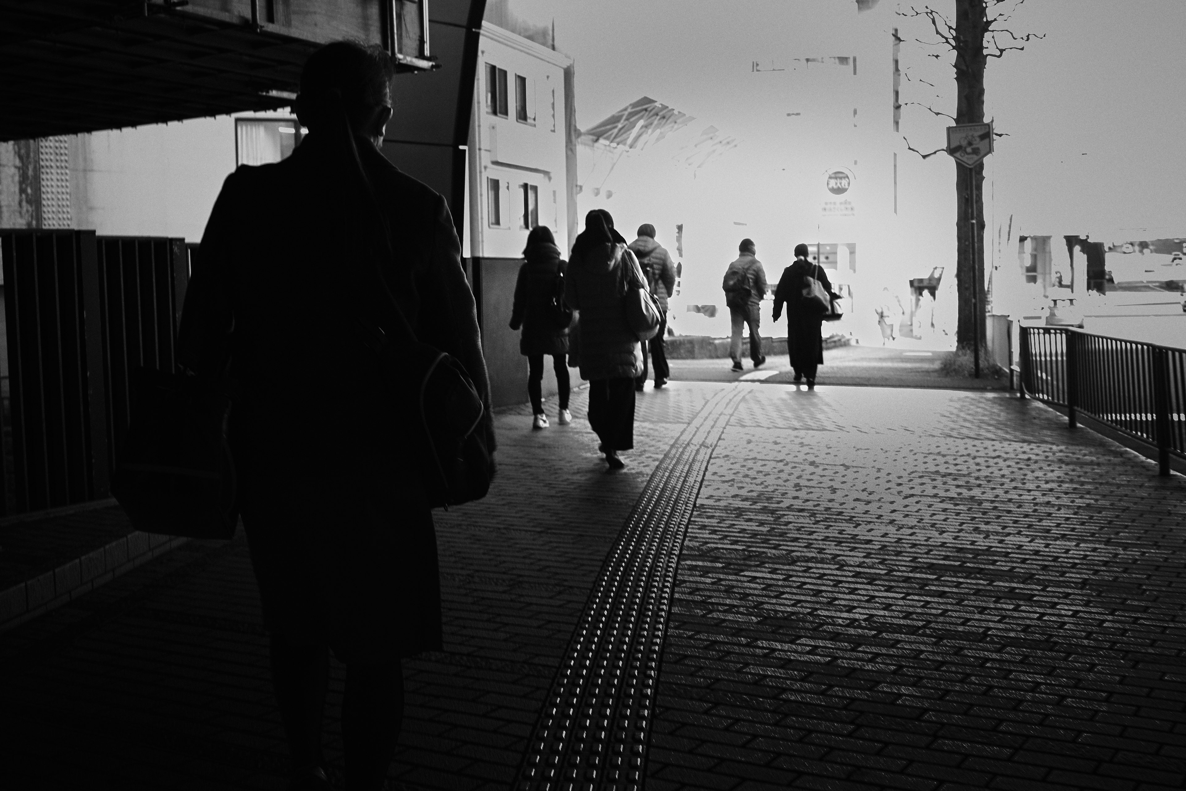 Scena di strada in bianco e nero con persone che camminano su un marciapiede in cemento