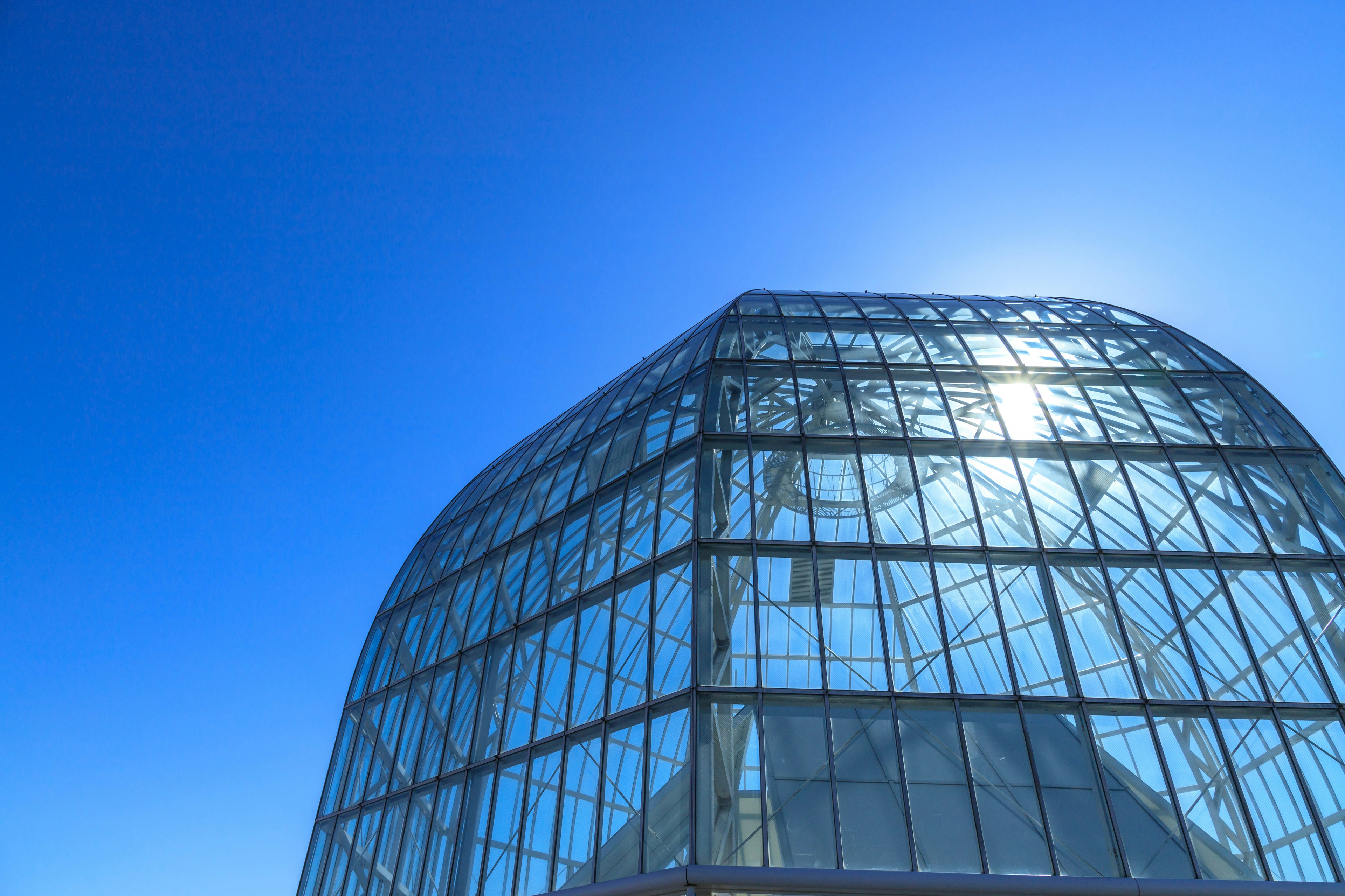 Part of a modern glass building under a clear blue sky