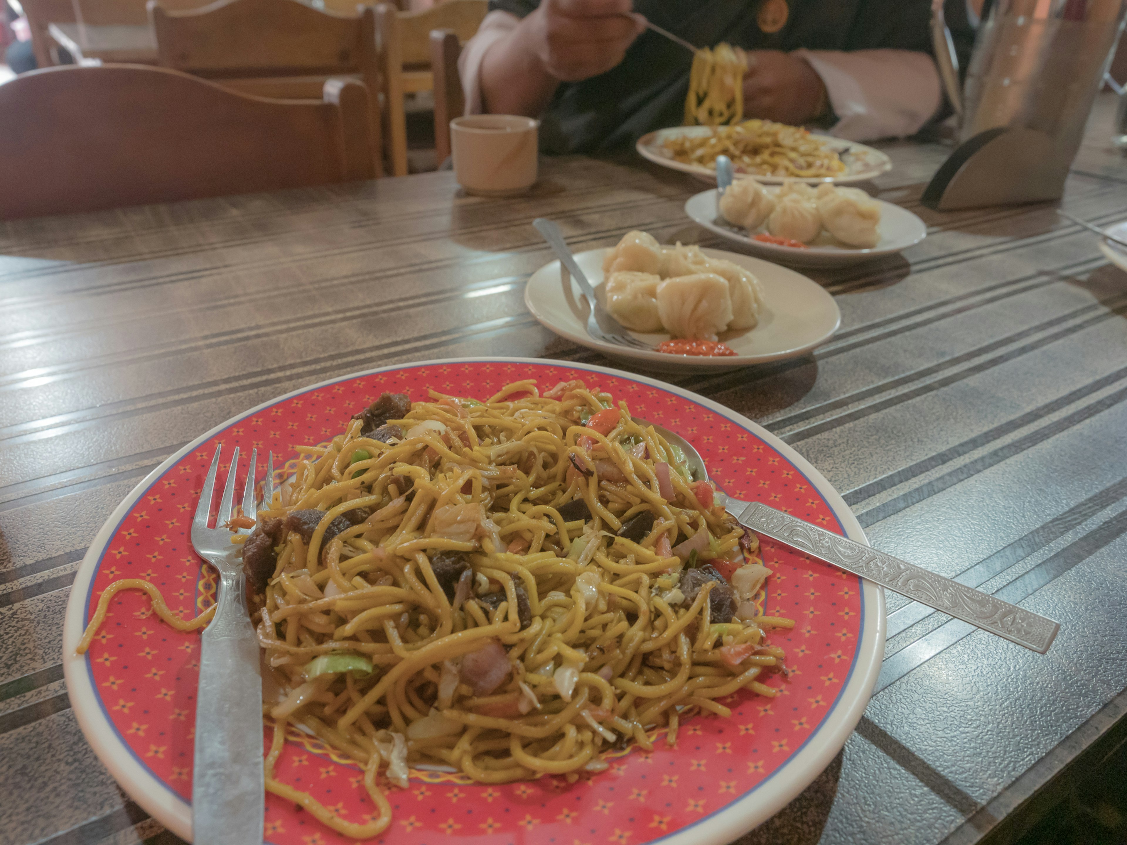 テーブルの上の皿に盛られた焼きそばとその背景にある他の料理