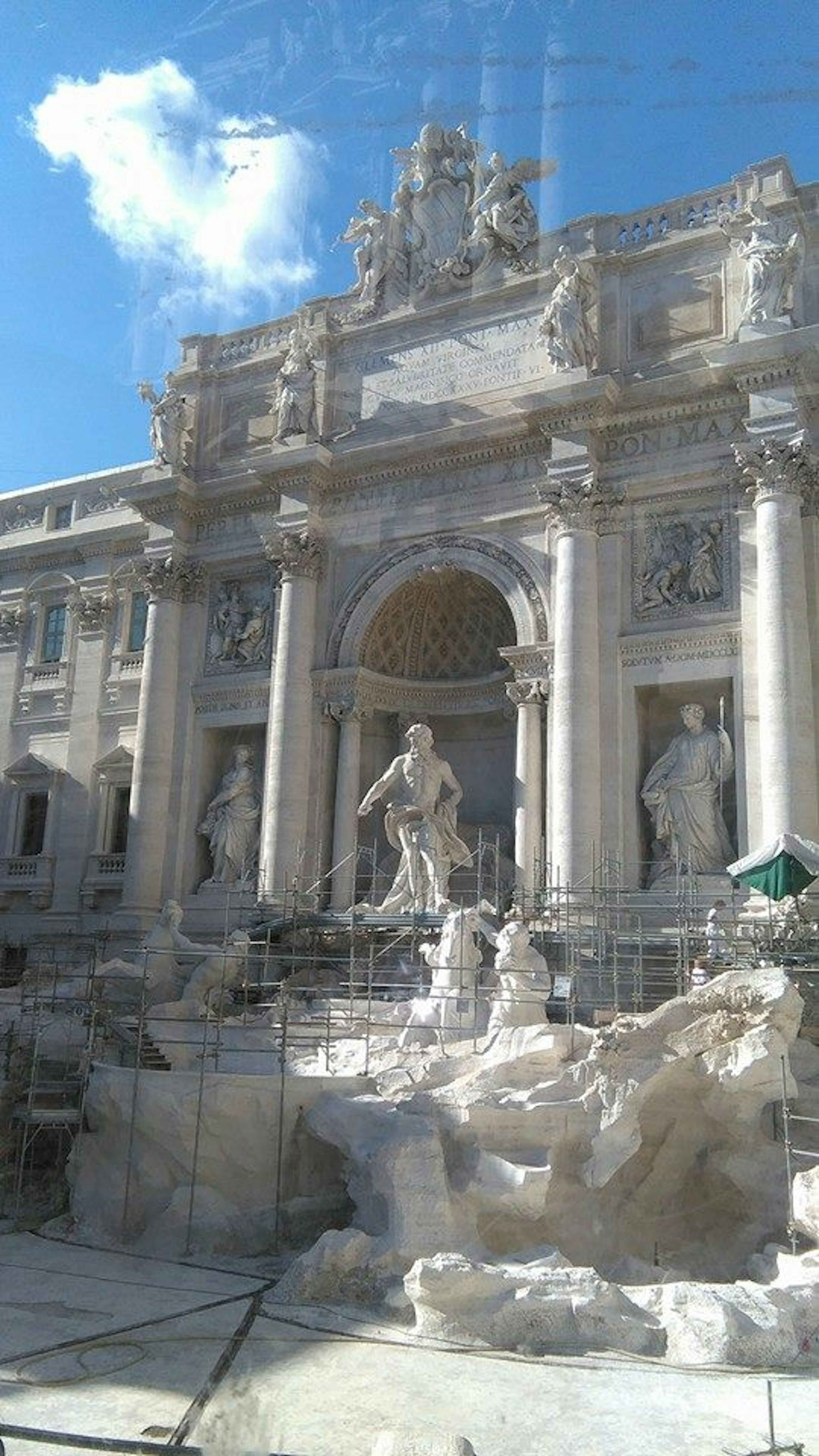 Blick auf den Trevi-Brunnen während der Restaurierung mit großen Skulpturen vor blauem Himmel