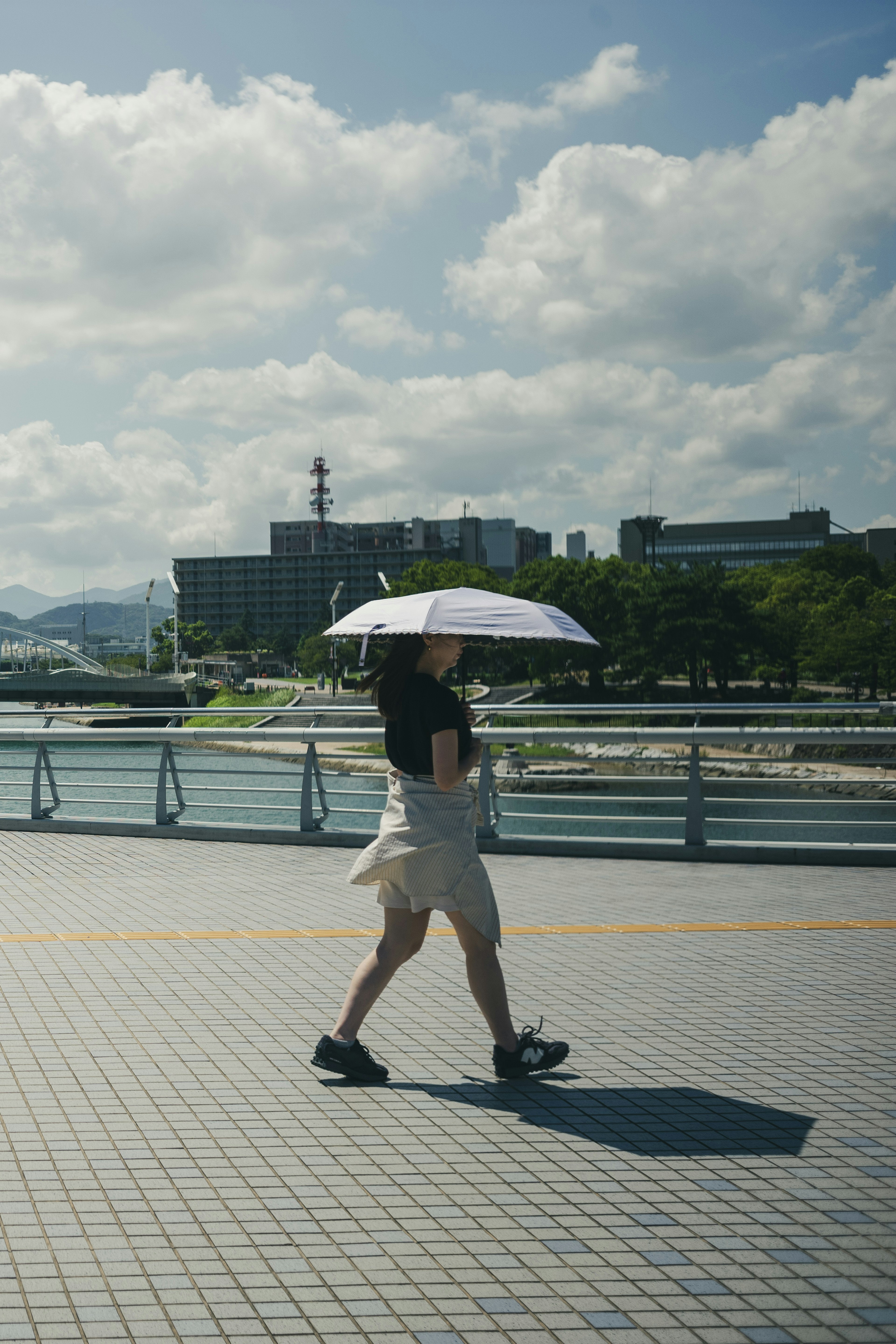 晴れた日、傘をさして歩く人が横切る風景