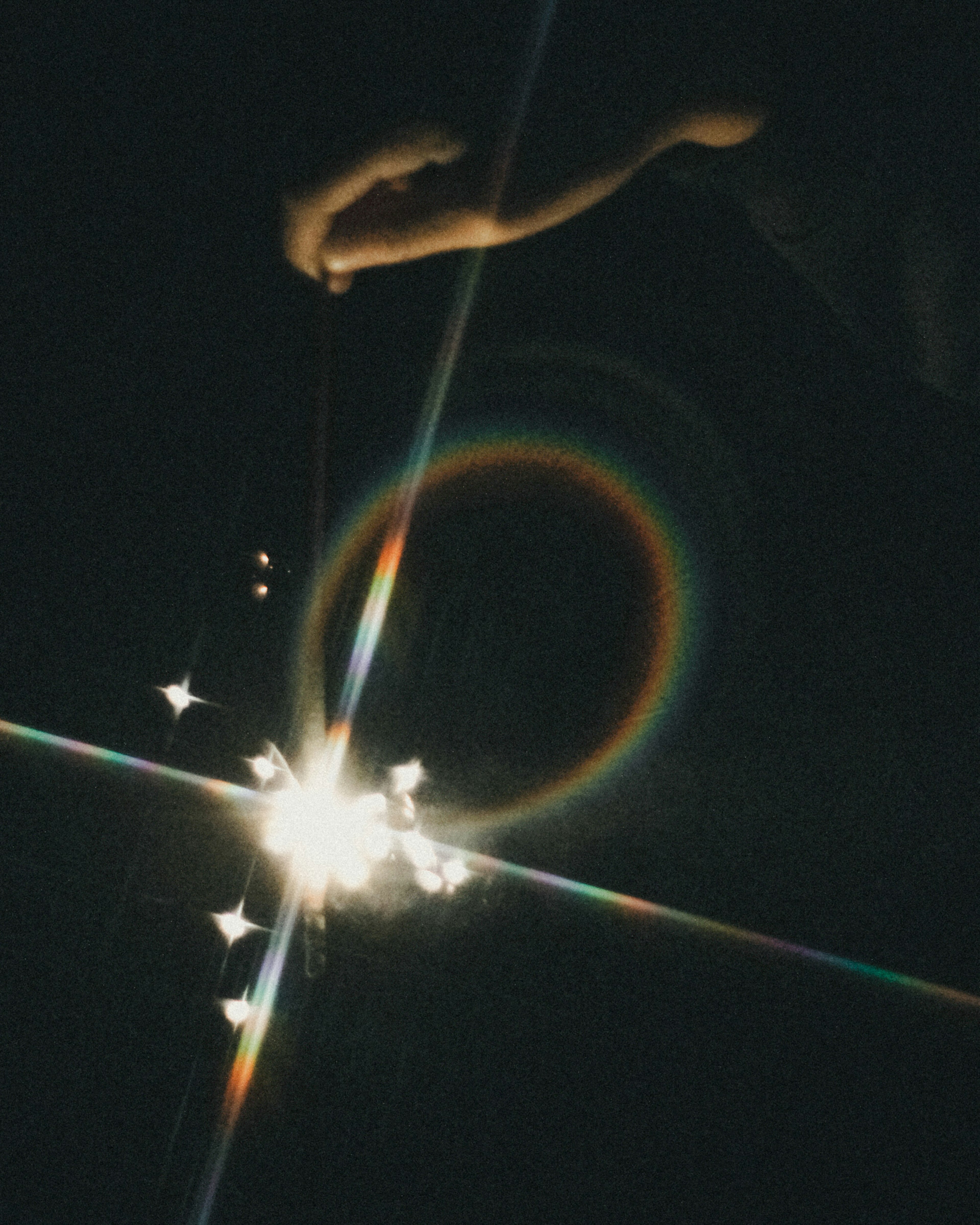 Una mano sosteniendo un fuego de artificio creando un halo de luz sobre un fondo oscuro