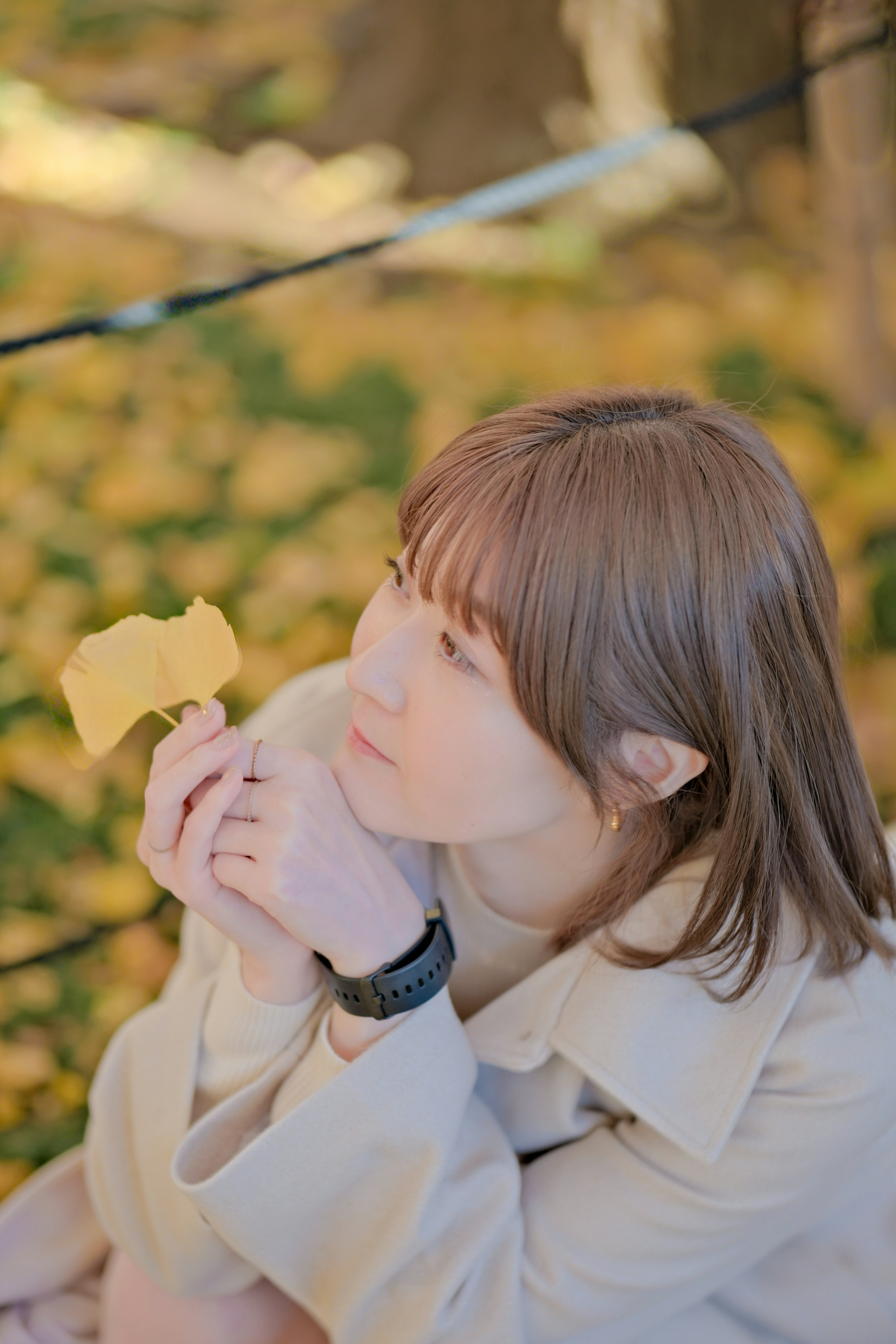 秋の葉を手に持つ女性が考え込む姿