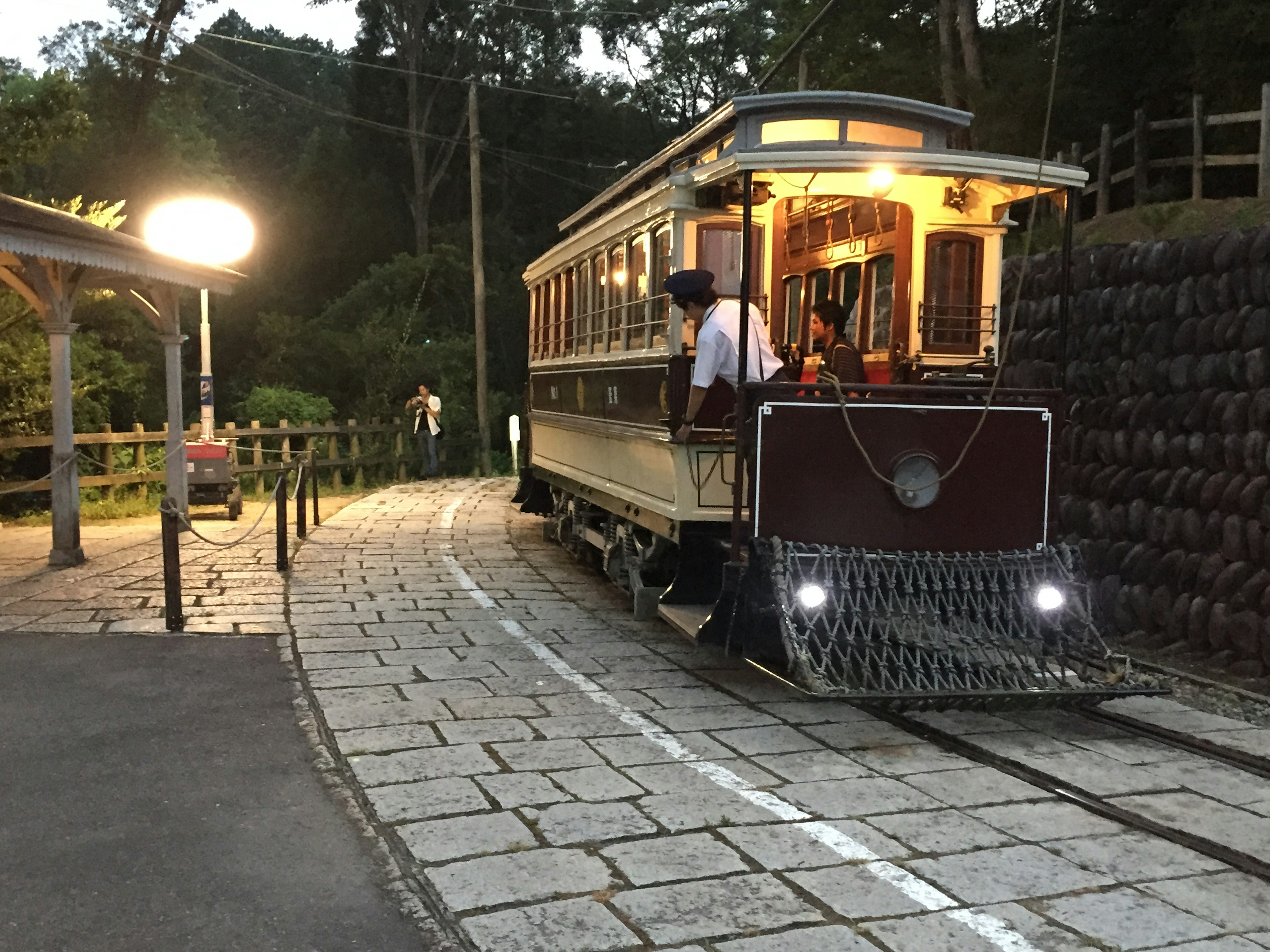 夜の山間に停車中のレトロなトロリー車両 照明が温かく周囲の自然と調和