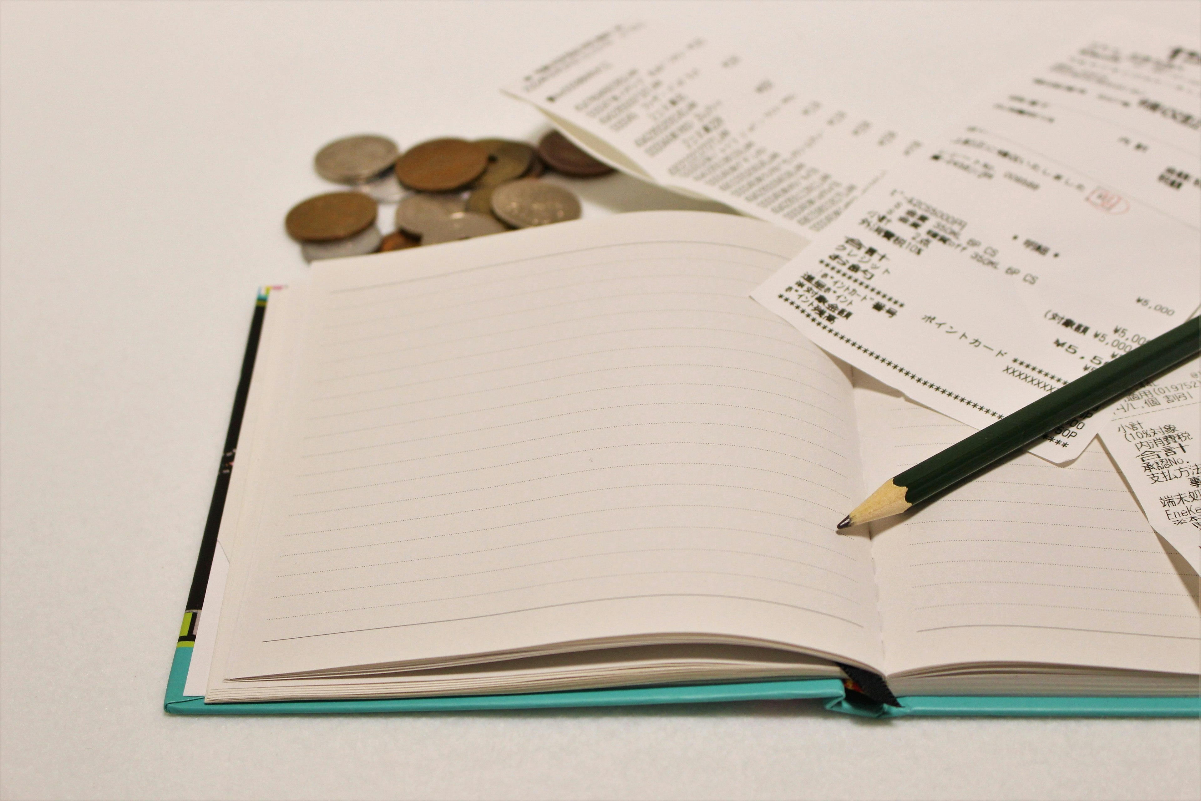 Image of a notebook, coins, and receipts on a white background