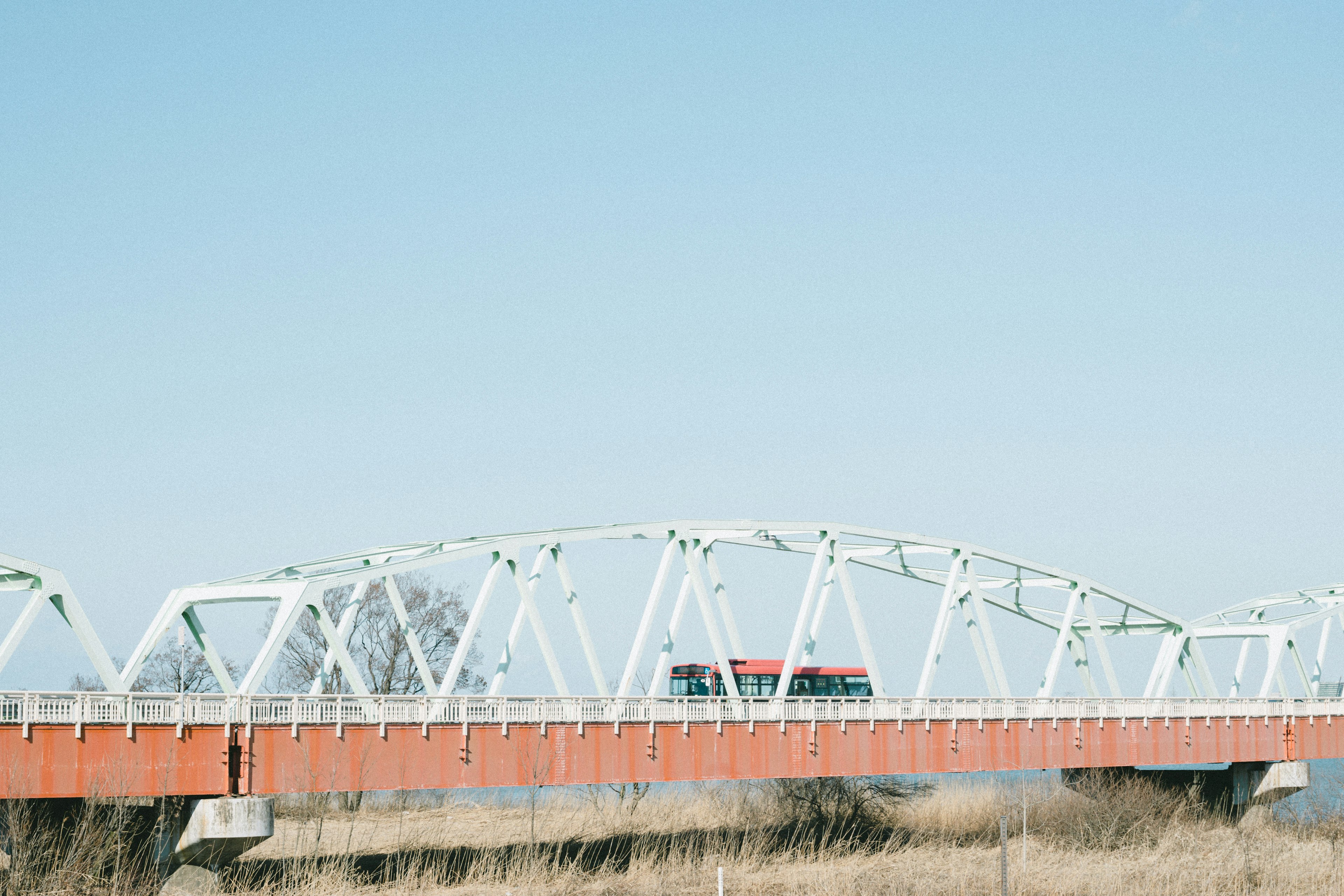 White bridge with red car under clear blue sky