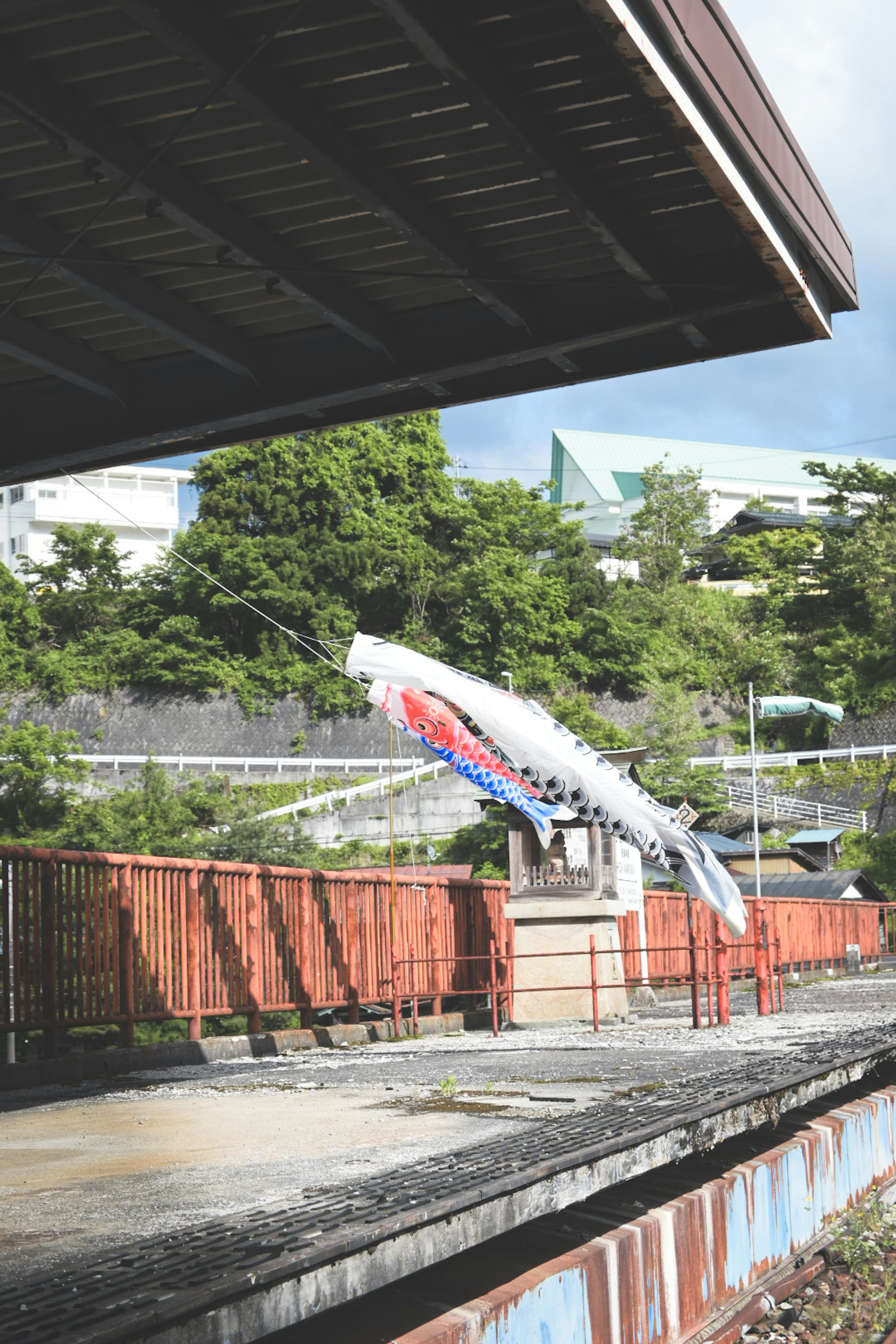 Koinobori sur une plateforme de train avec une verdure luxuriante en arrière-plan