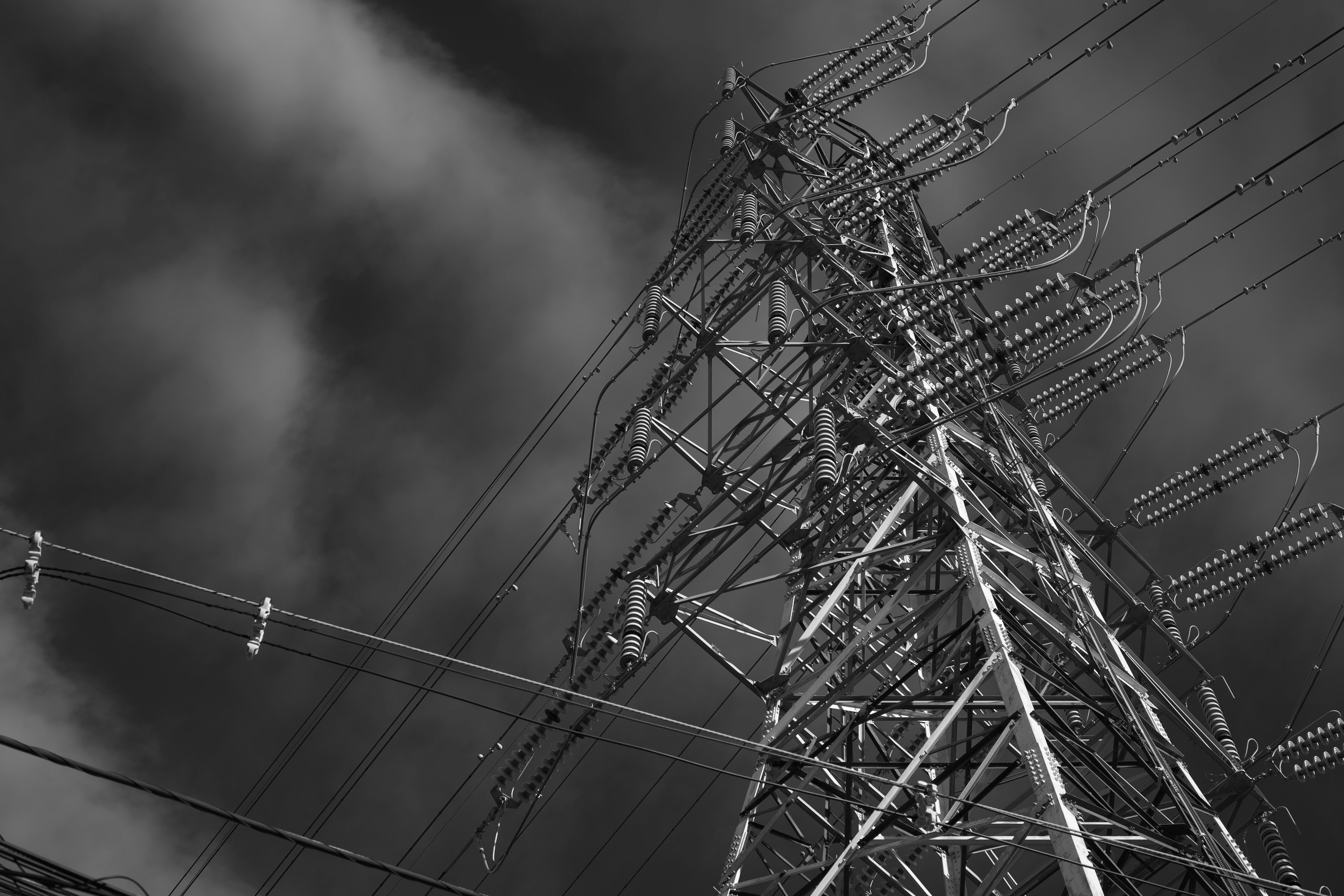 High voltage power lines tower under a cloudy sky