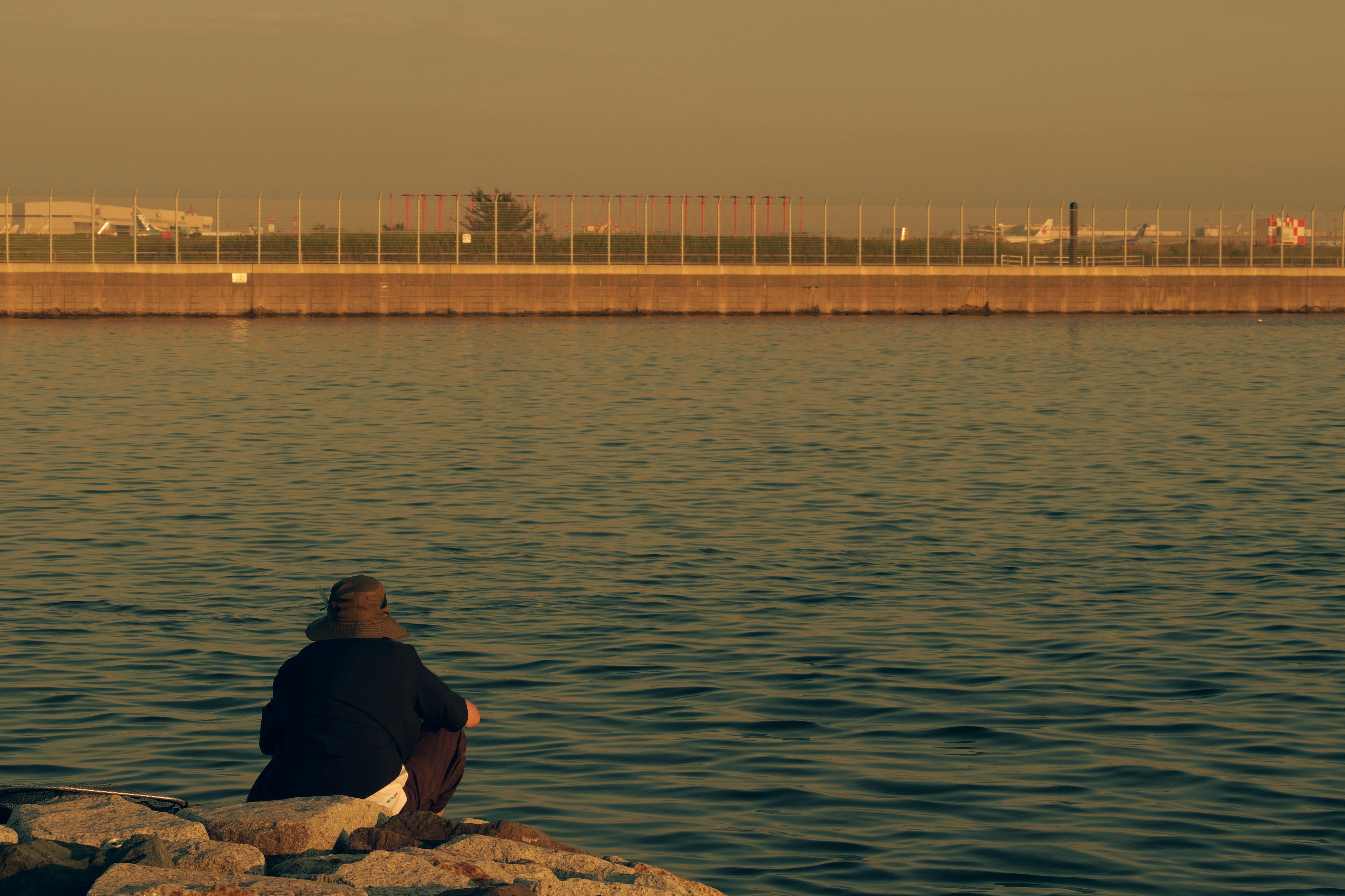 Silhouette di una persona che guarda l'acqua calma al tramonto sulla spiaggia