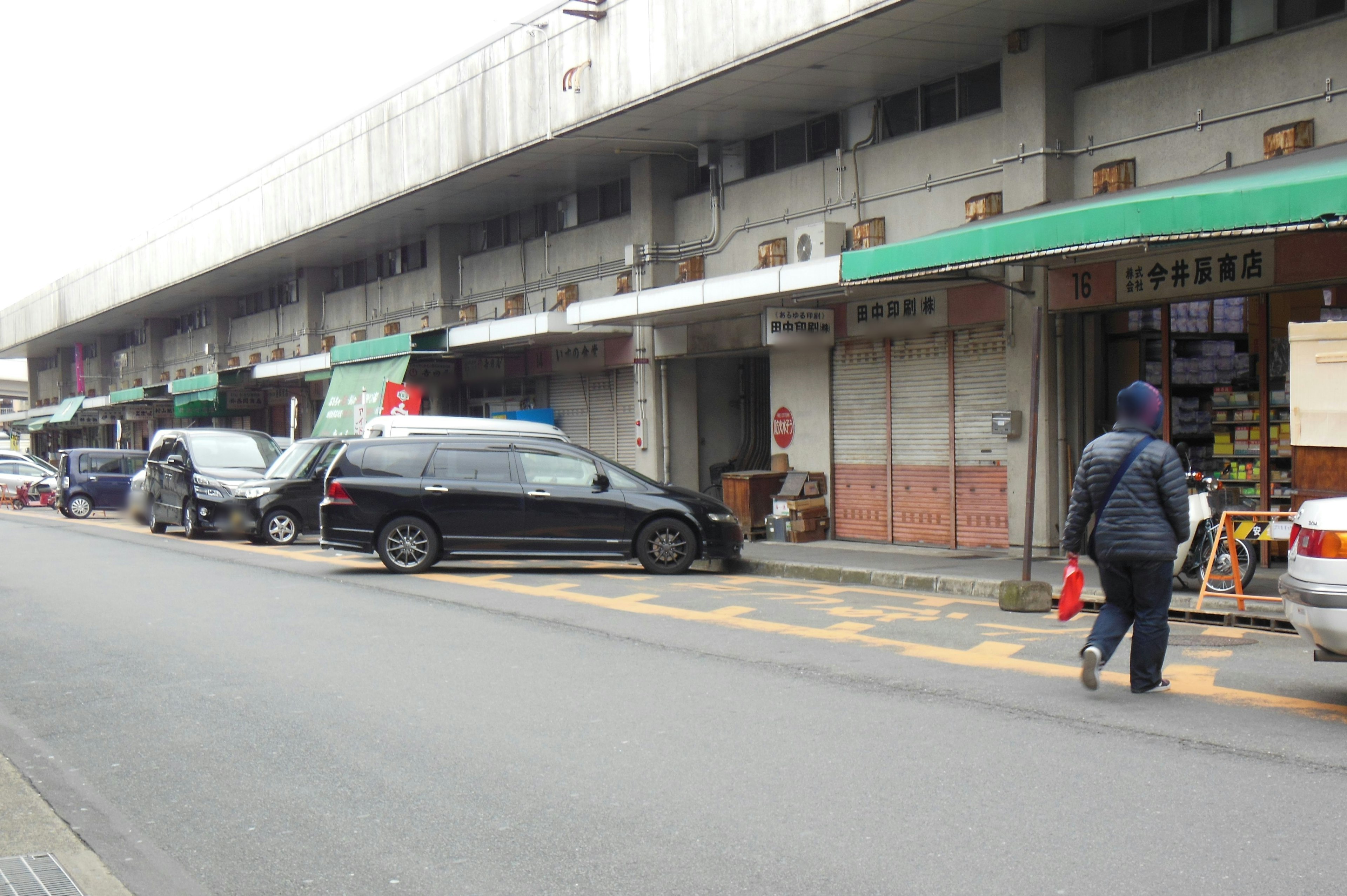 Pemandangan jalan dengan bangunan komersial rendah dan mobil terparkir