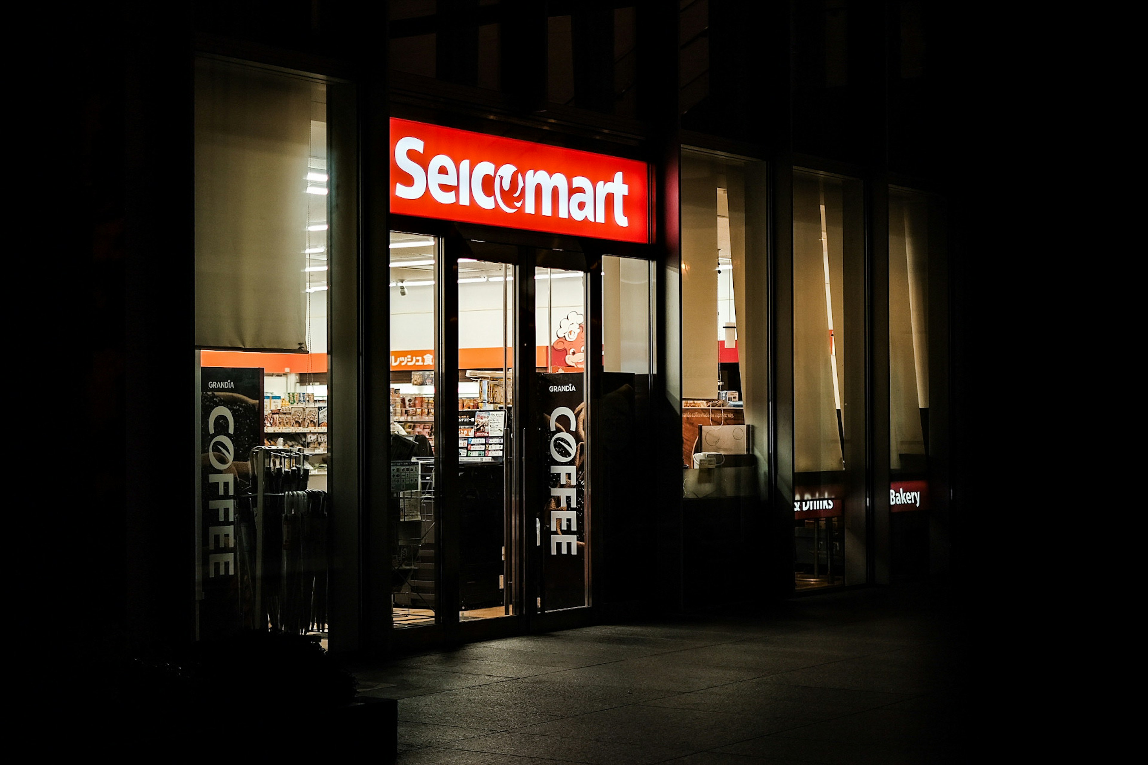 Seicomart storefront with bright sign and glass doors at night