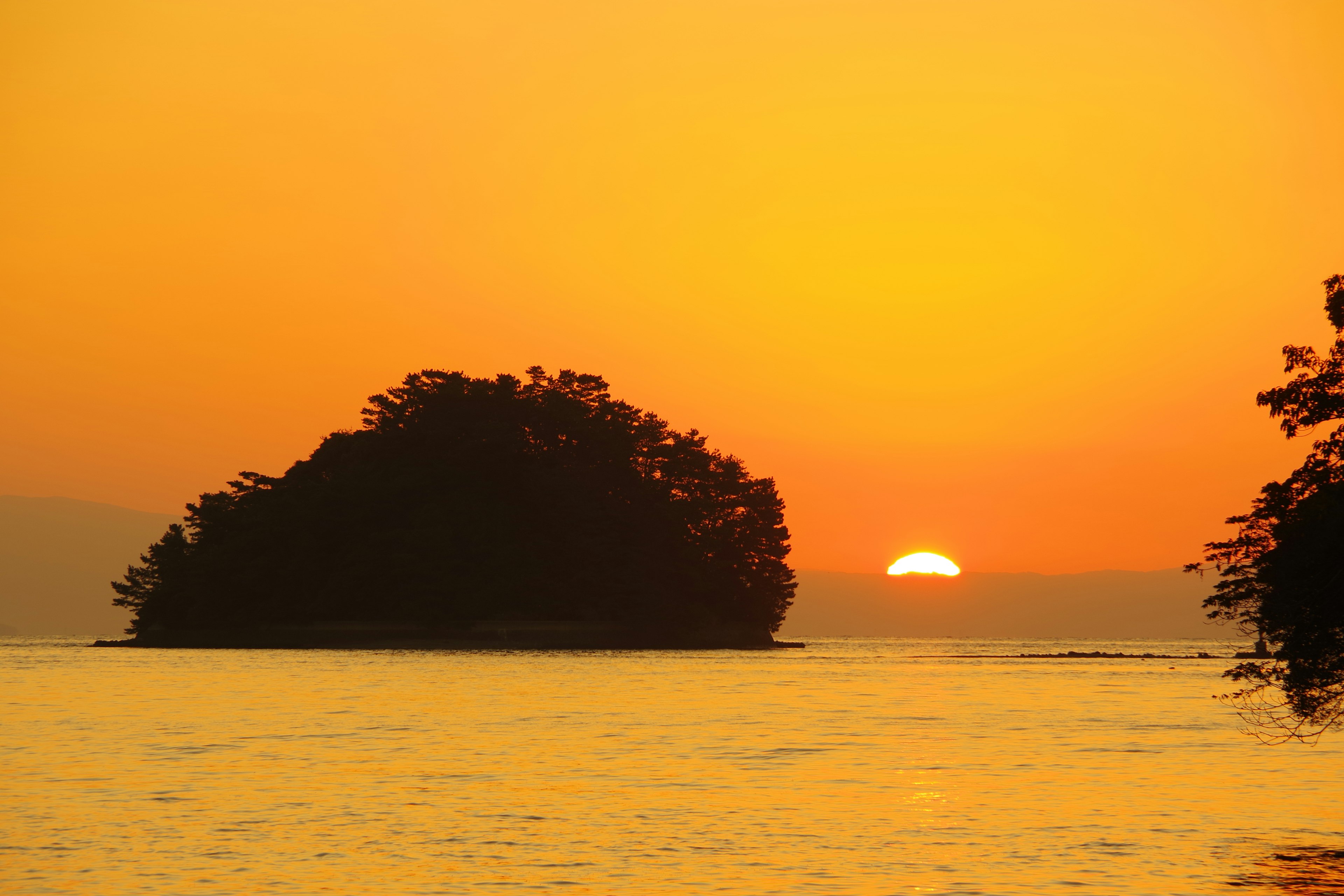 Schöner Sonnenuntergang mit orangefarbenem Himmel hinter einer kleinen Insel