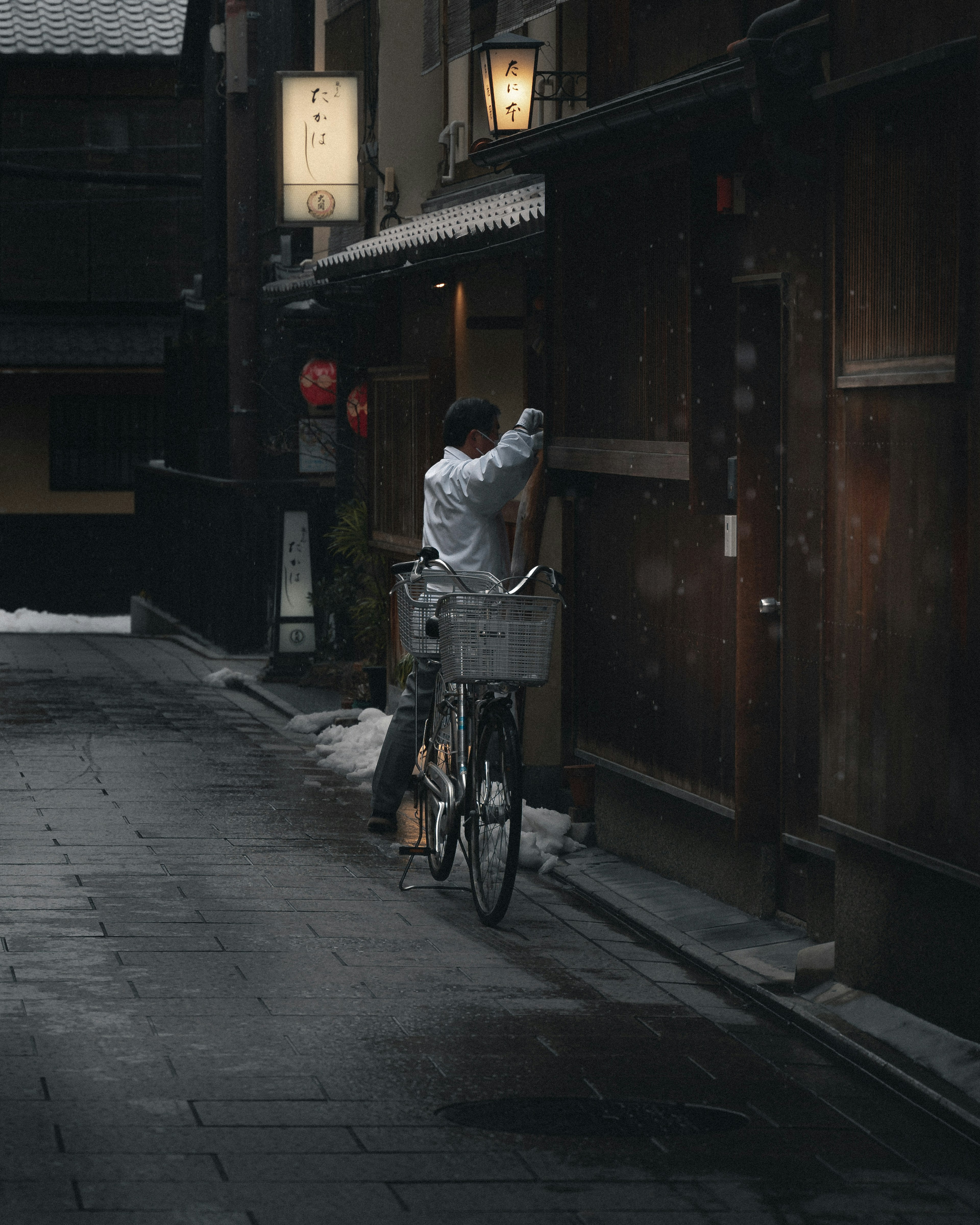 静かな路地で自転車を使っている男性 古い建物の前で何かを確認している