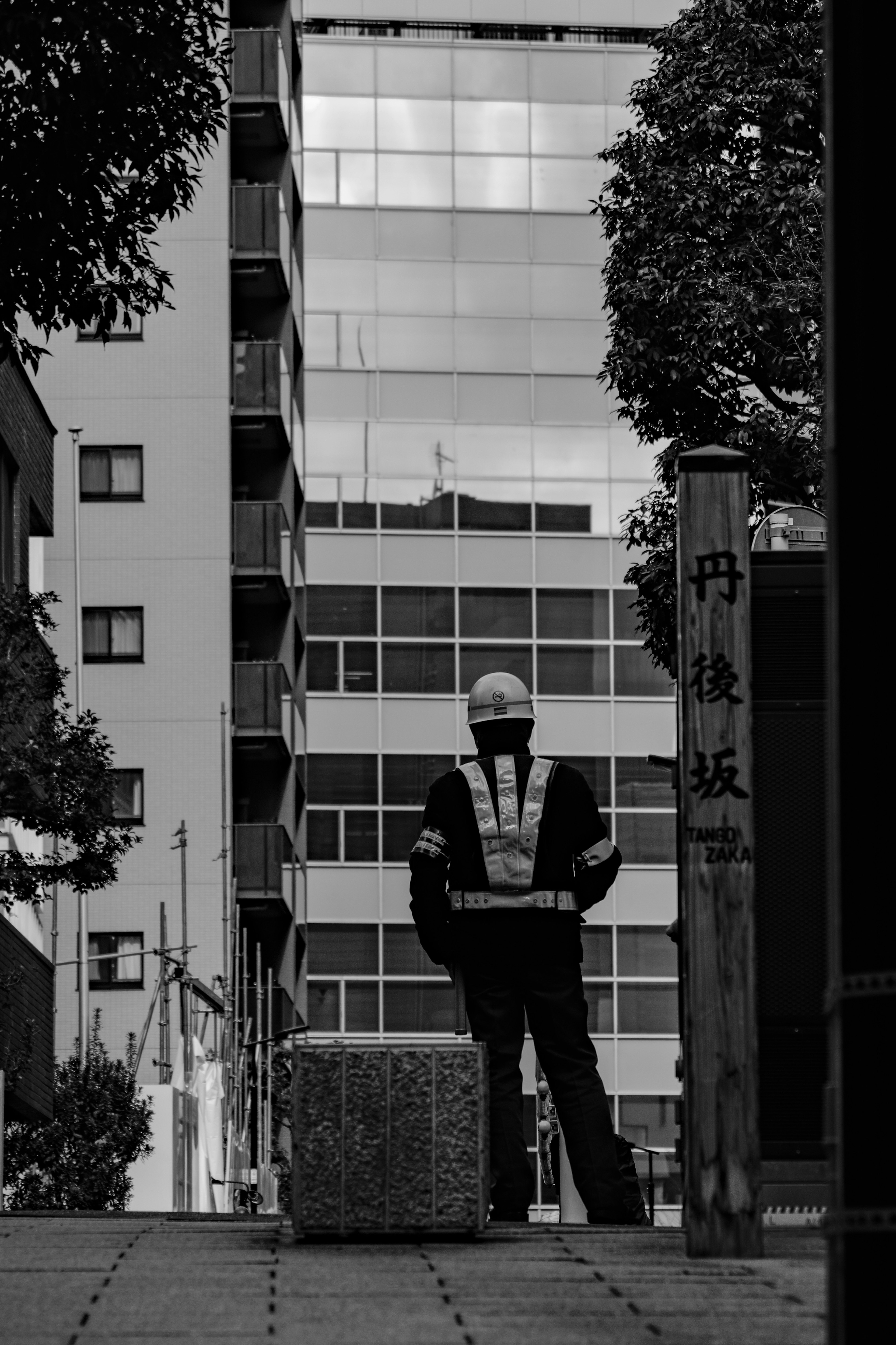 A construction worker standing with his back to the camera in a monochrome photo