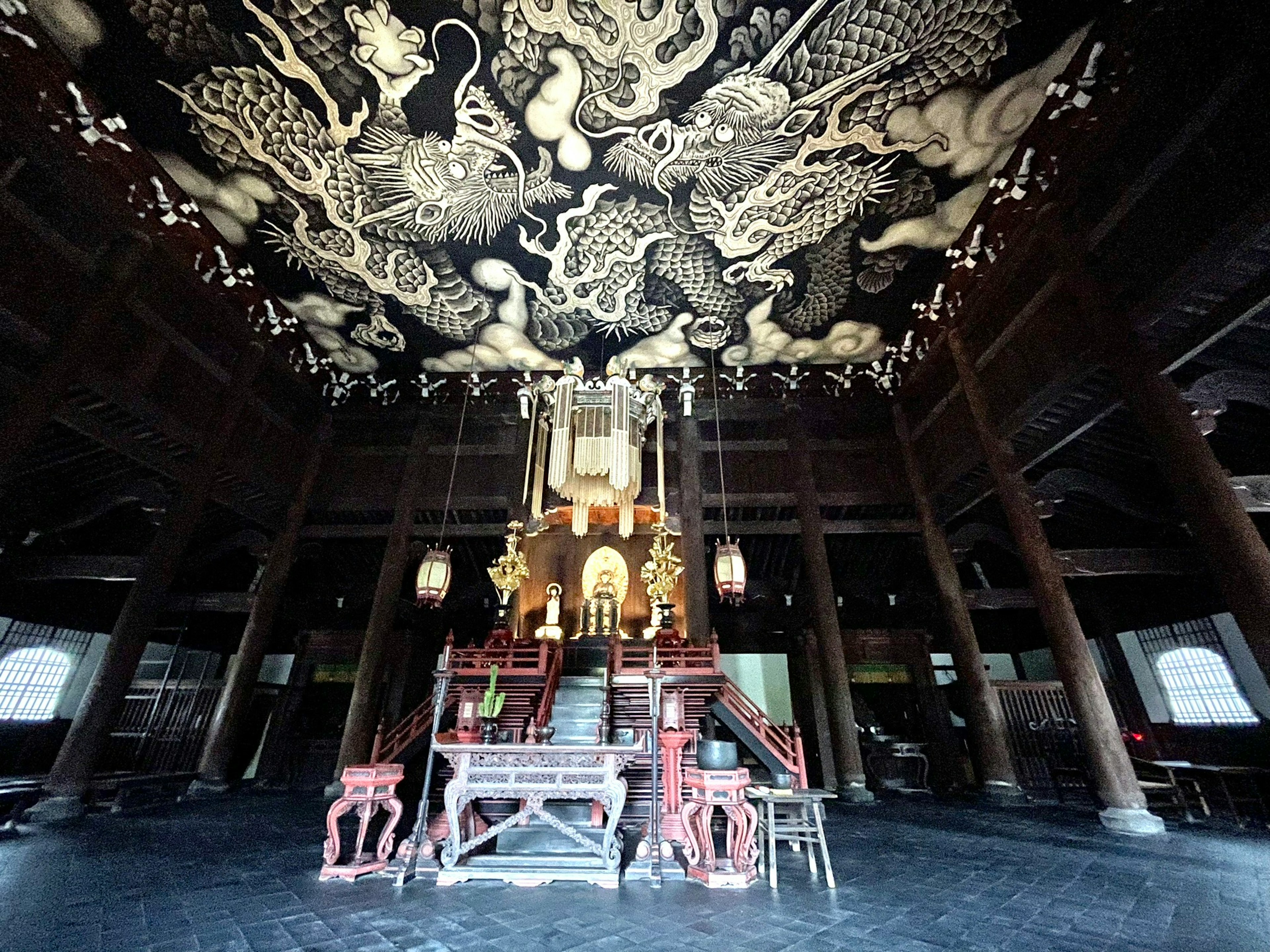 Interior de un templo con decoraciones elaboradas un techo con dragones y una estatua de Buda dorada