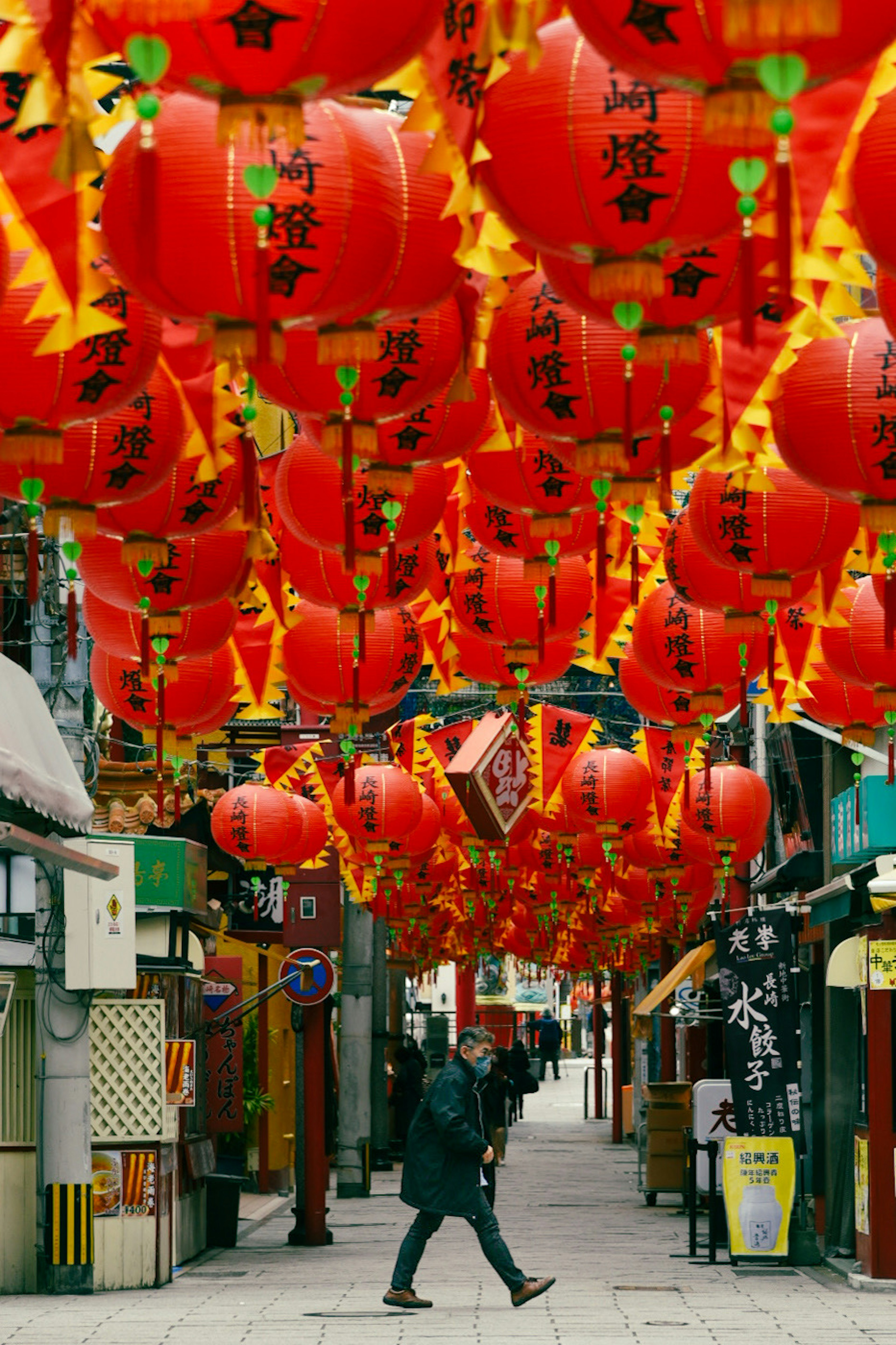 A person walking under red lanterns in a vibrant street