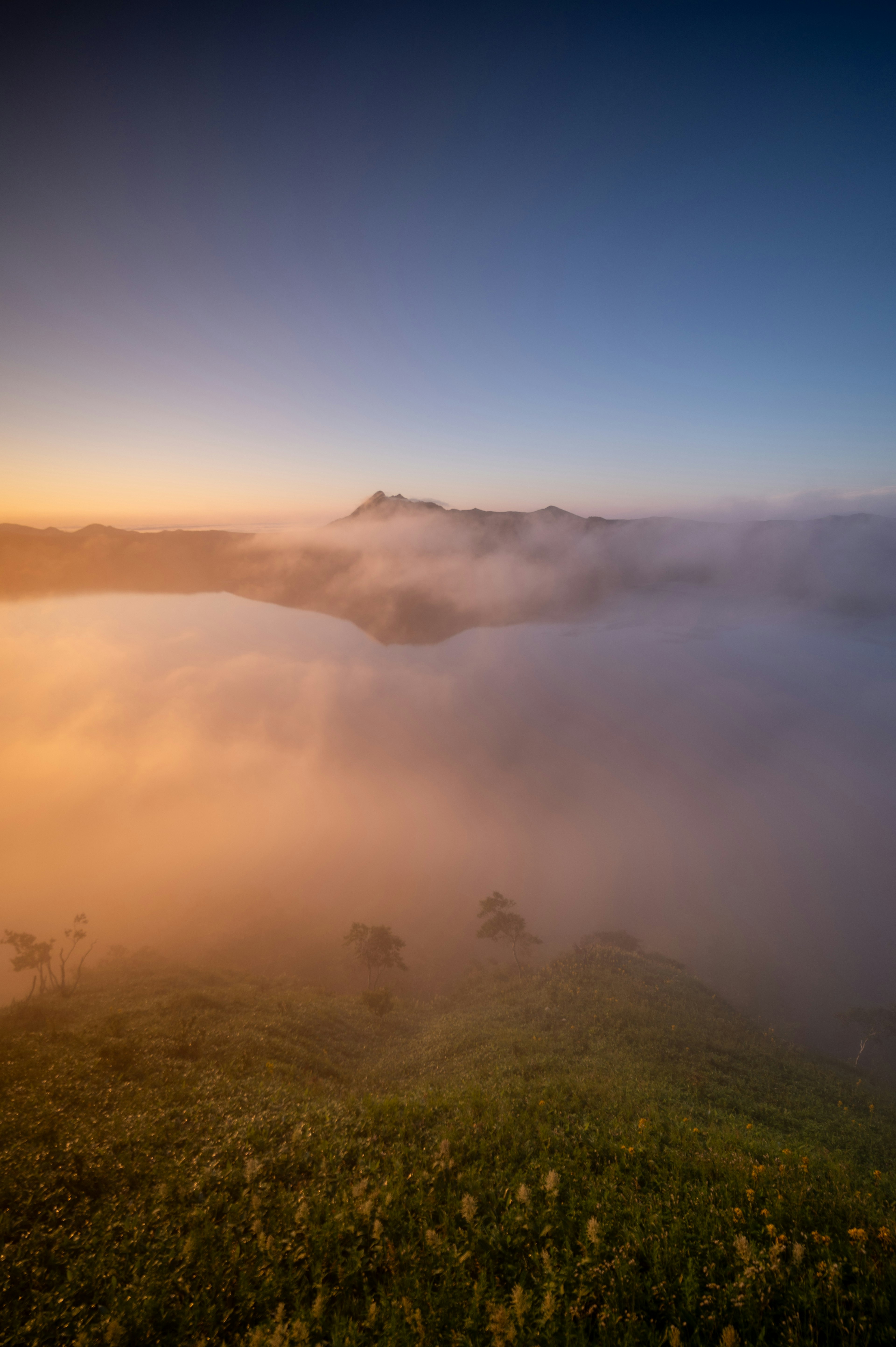 Montagne avvolte nella nebbia con cielo blu all'alba