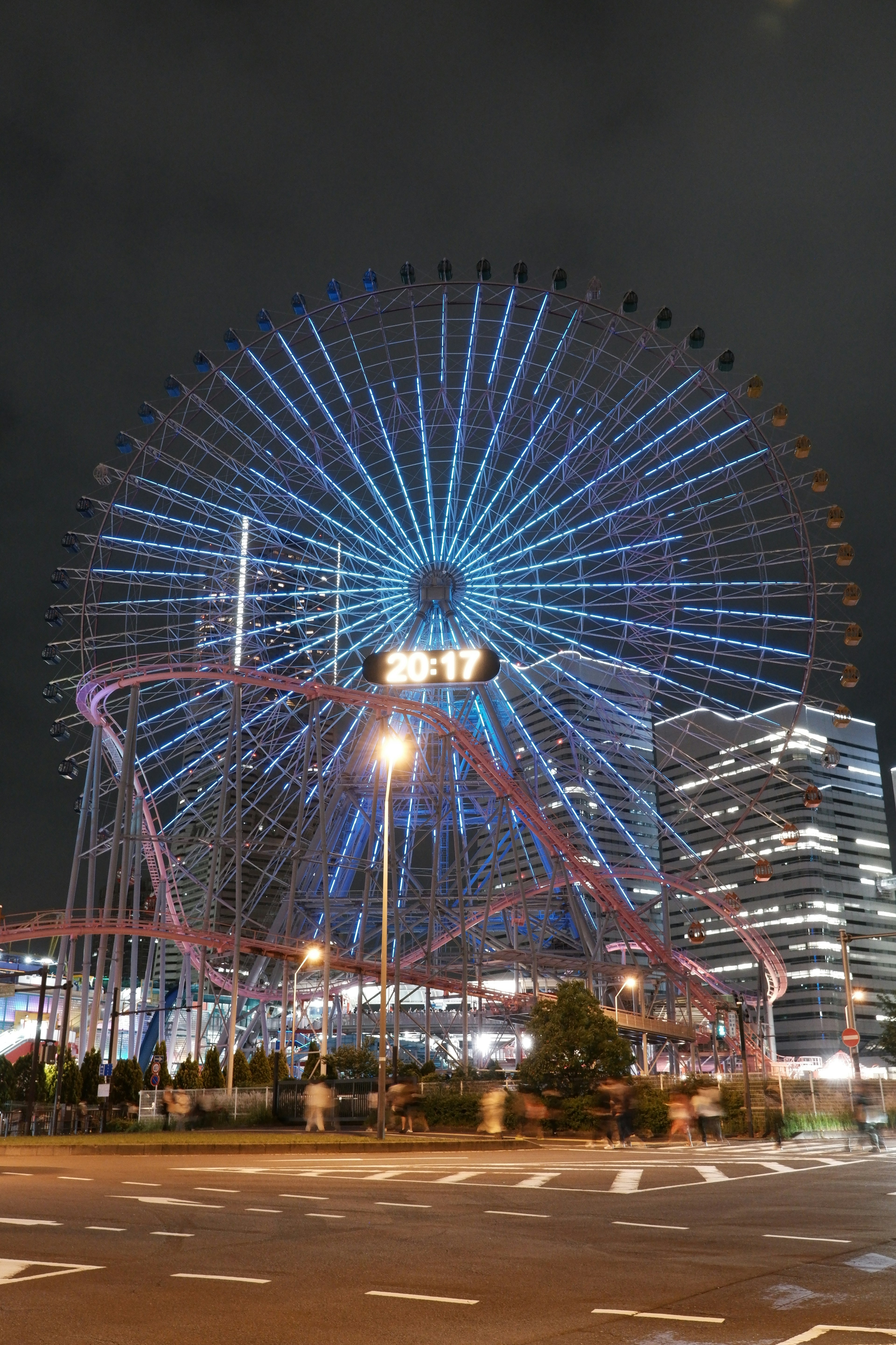 Night view of a Ferris wheel illuminated in blue lights in an urban setting