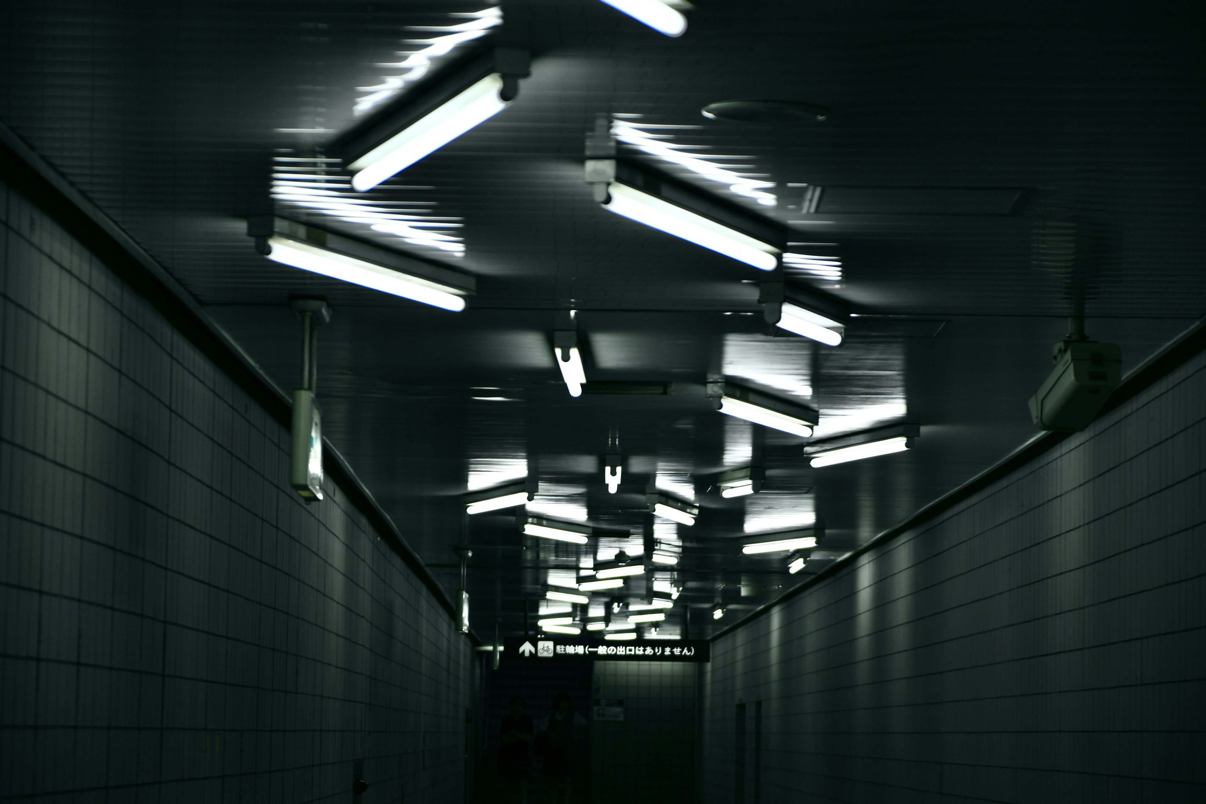 Dimly lit tunnel with irregular fluorescent lights on the ceiling