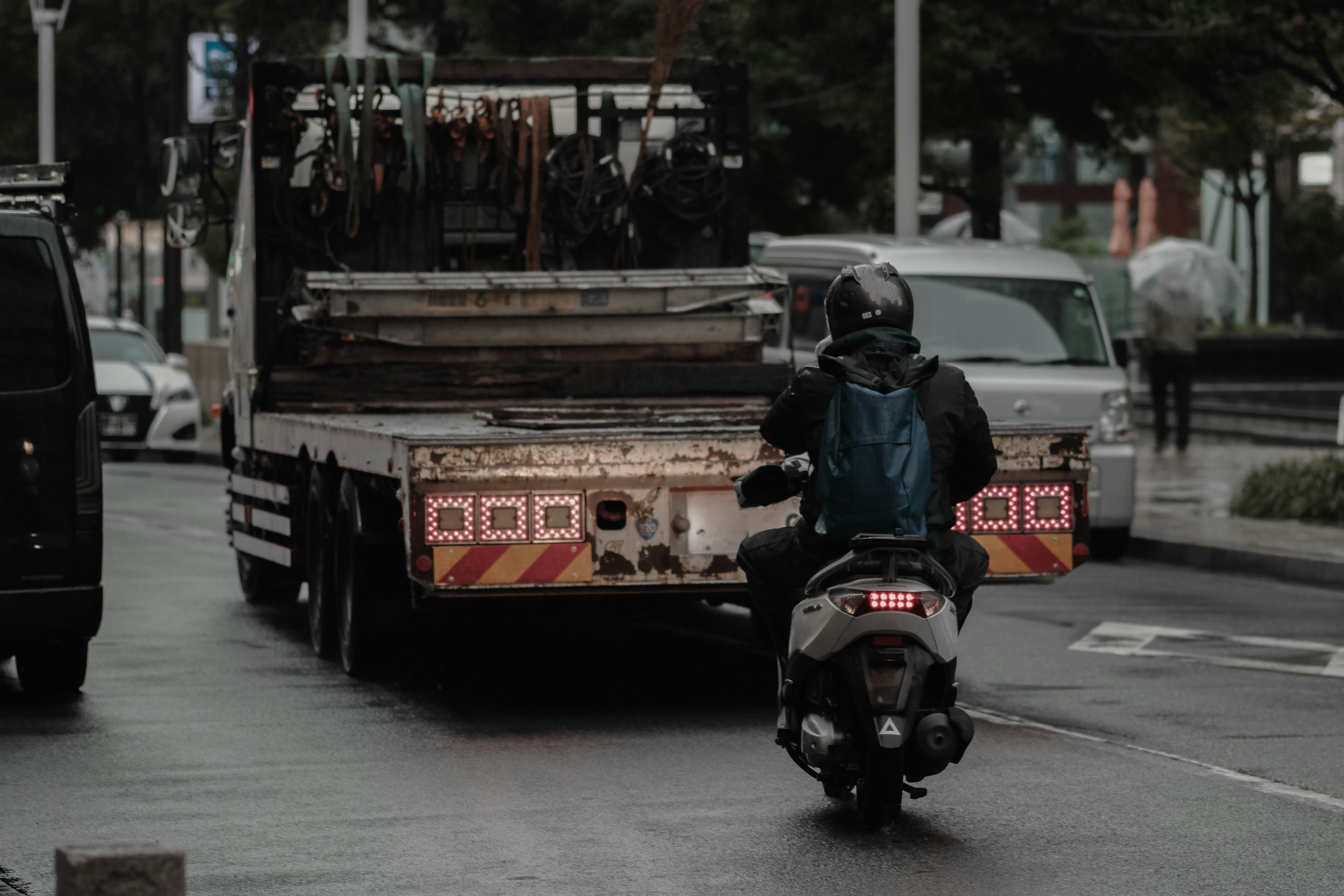 Eine Person auf einem Motorrad, die hinter einem Lastwagen in einer städtischen Umgebung fährt