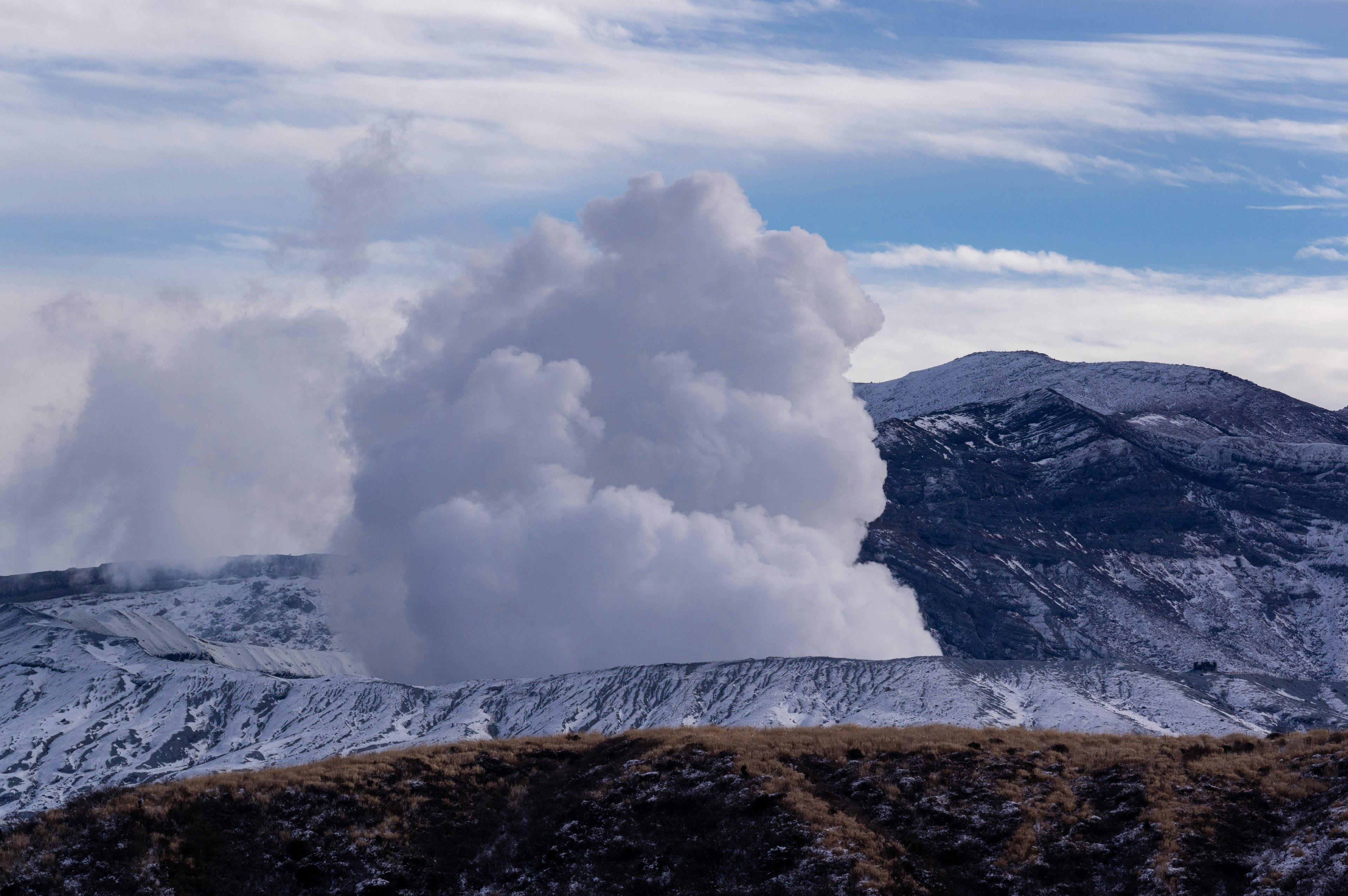 Vulkan, der Dampf gegen einen schneebedeckten Berghintergrund ausstößt