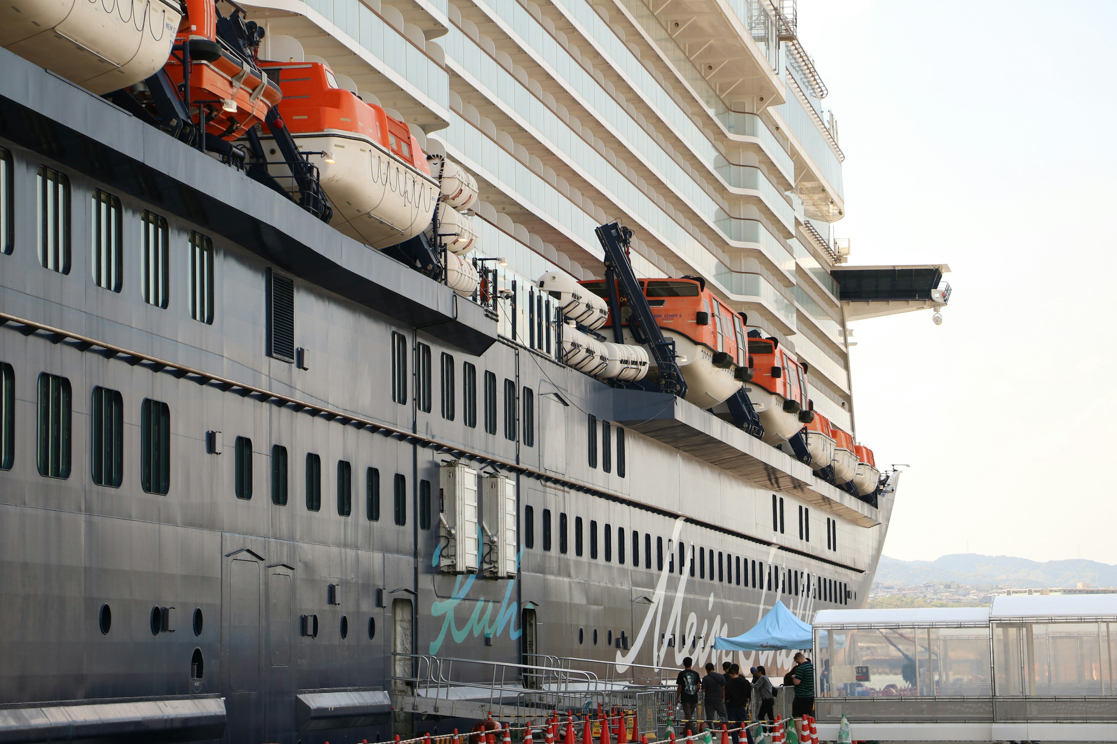 Imagen de un crucero de lujo mostrando el costado con casco negro y botes salvavidas rojos