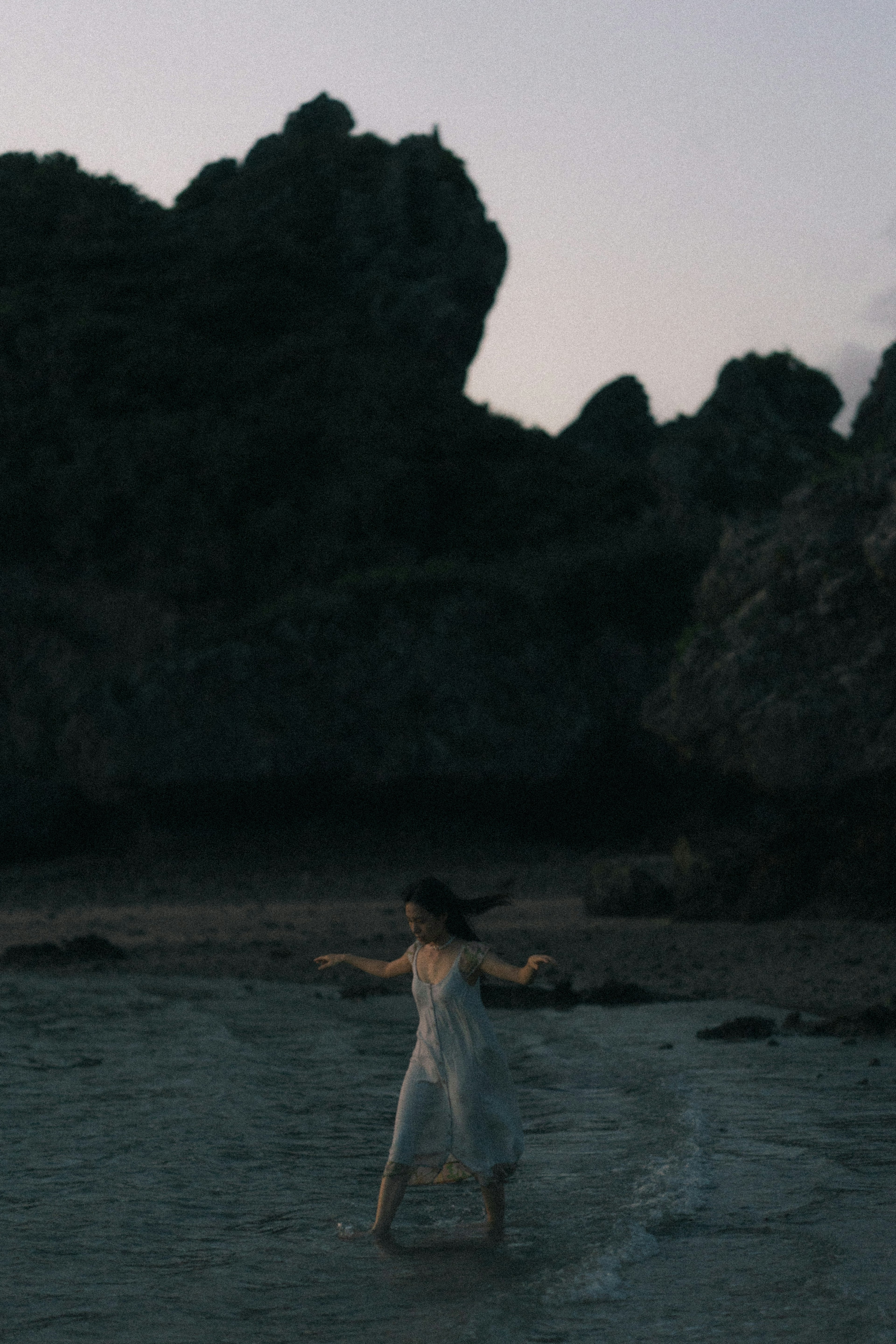 A woman in a white dress joyfully walking on the beach