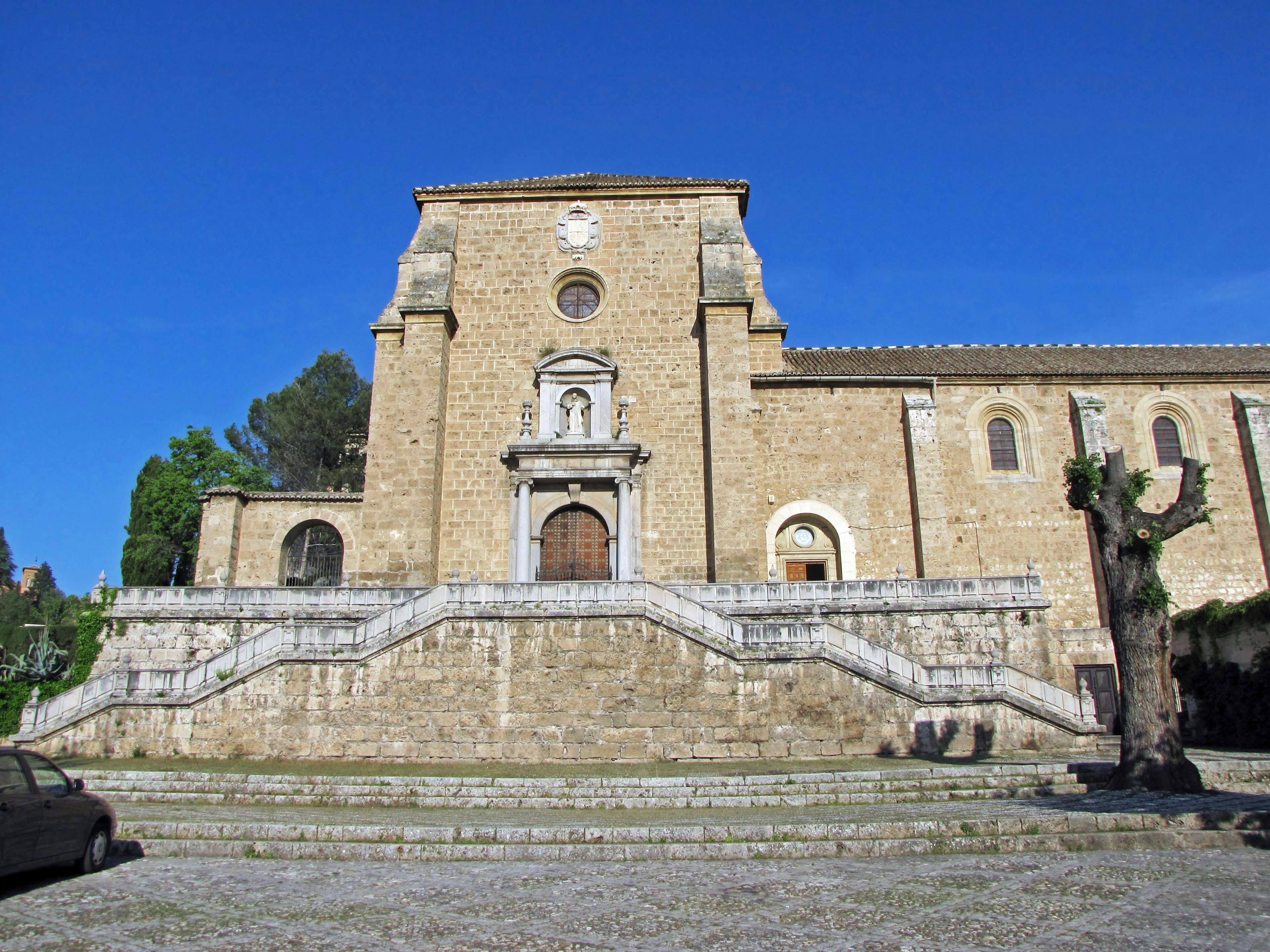 Stone church facade with grand staircase under a clear blue sky