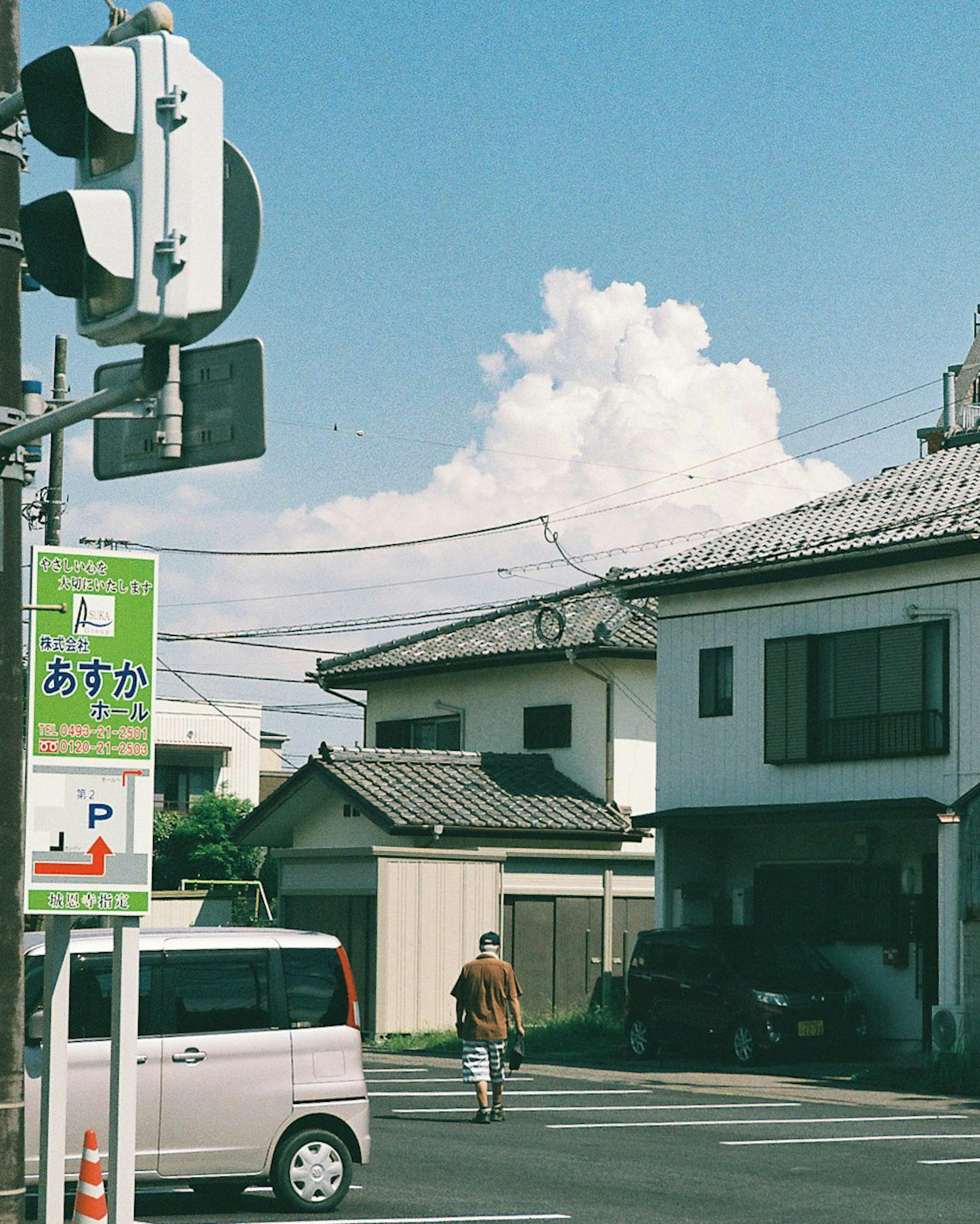 A person walking in a residential area under a blue sky