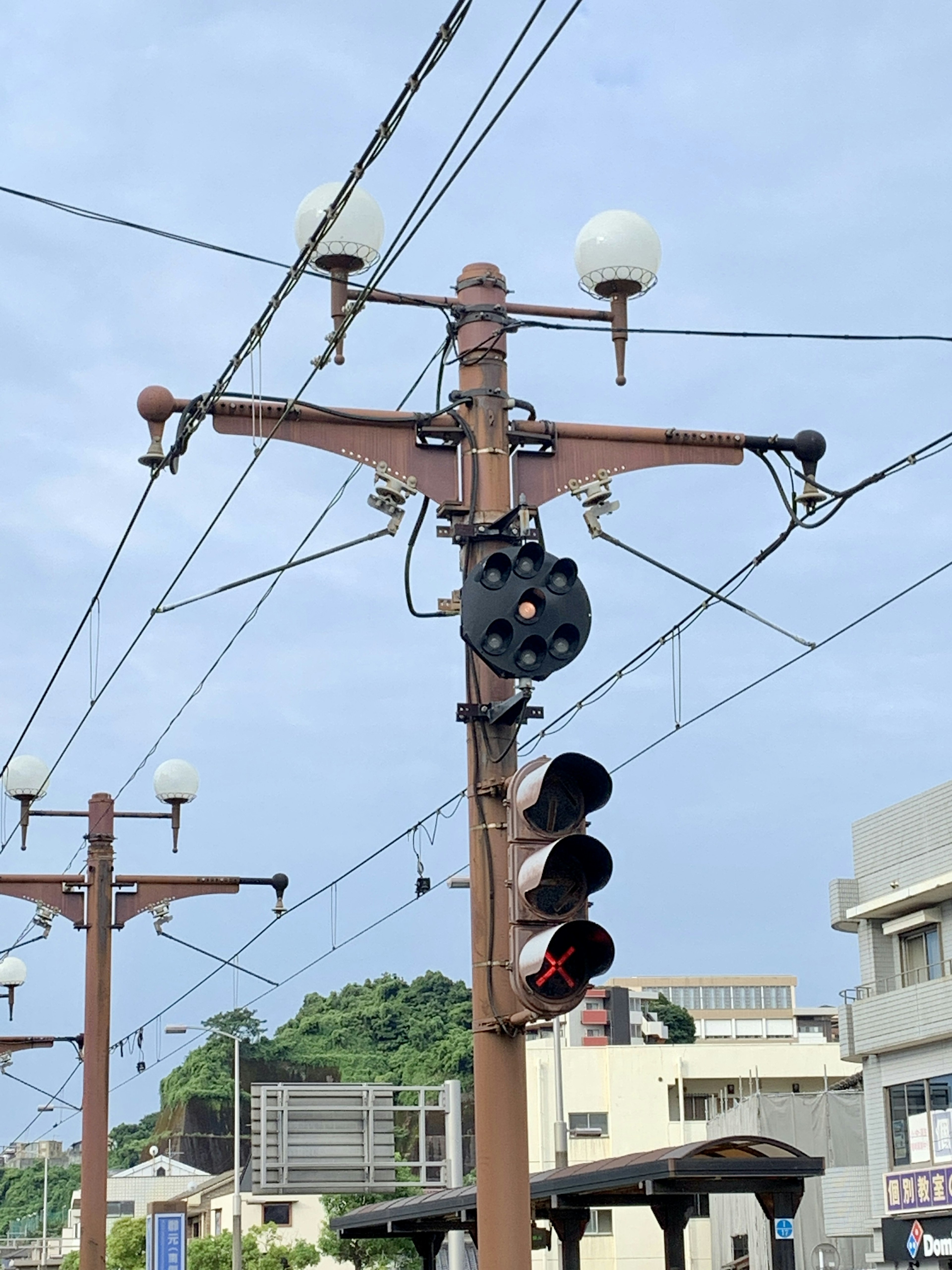 茶色の電柱に取り付けられた信号機と街灯が見える風景