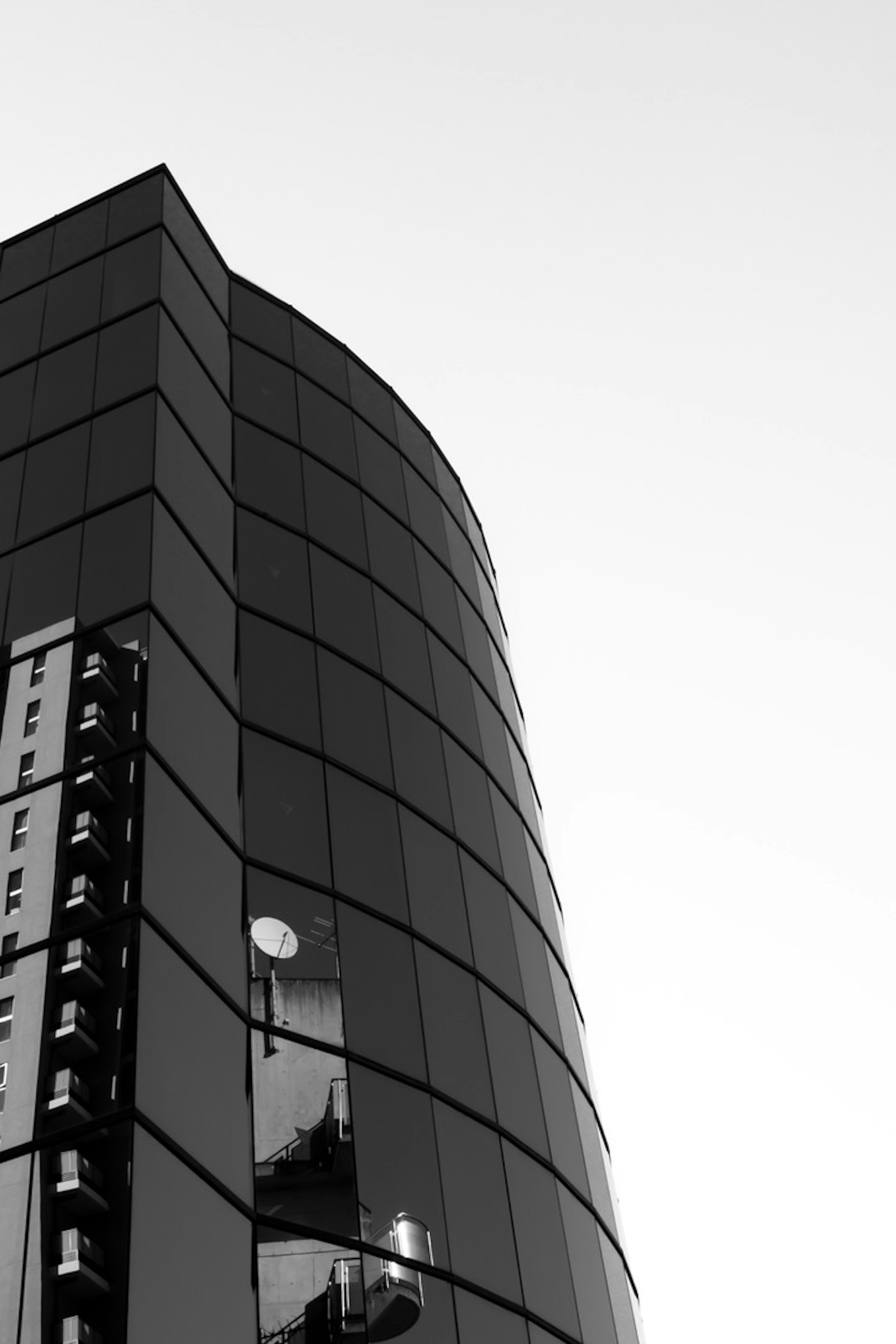 Curved upper section of a high-rise building captured in black and white