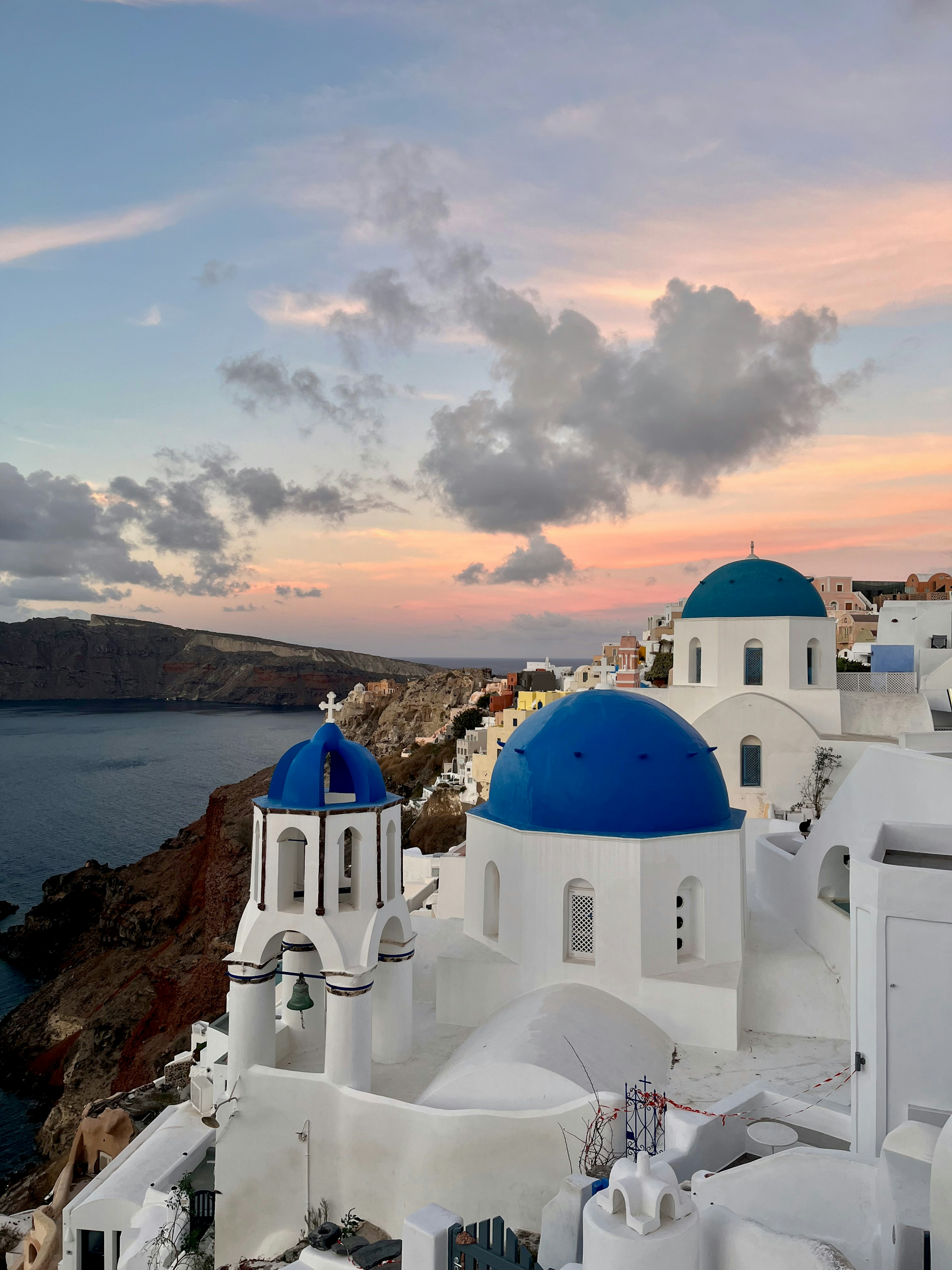 Santorini Landschaft mit weißen Gebäuden und blauen Kuppelkirchen bei Sonnenuntergang