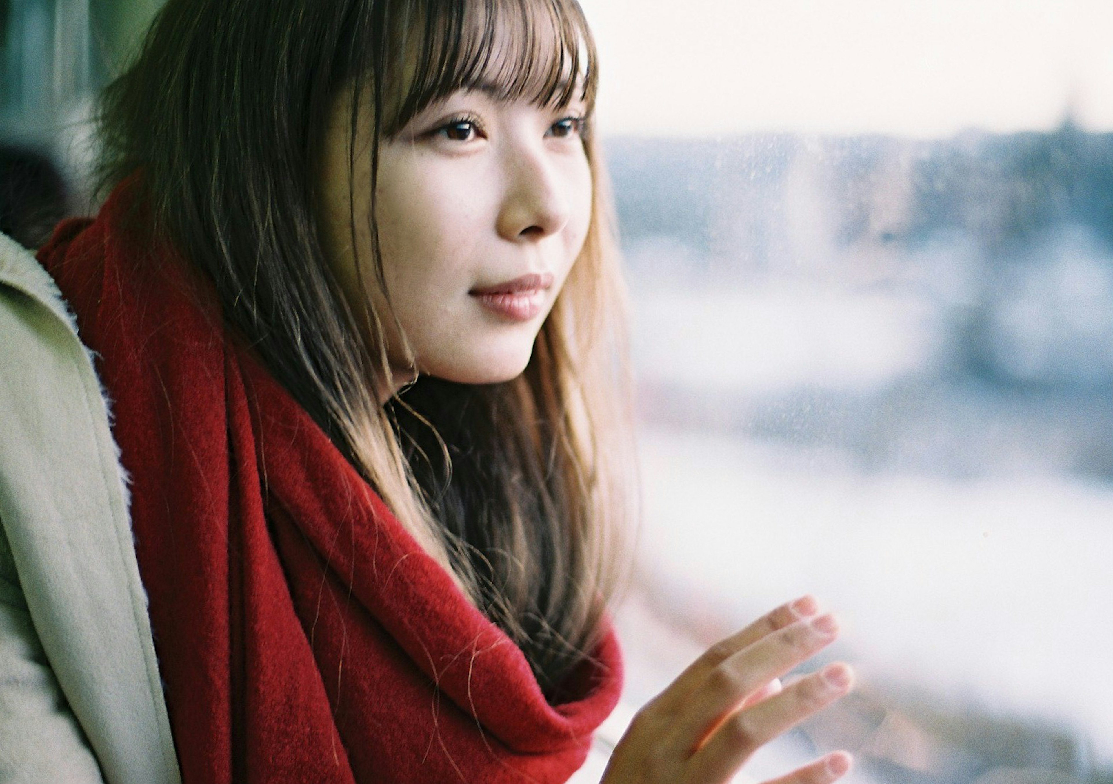 A woman in a red scarf gazing out the window