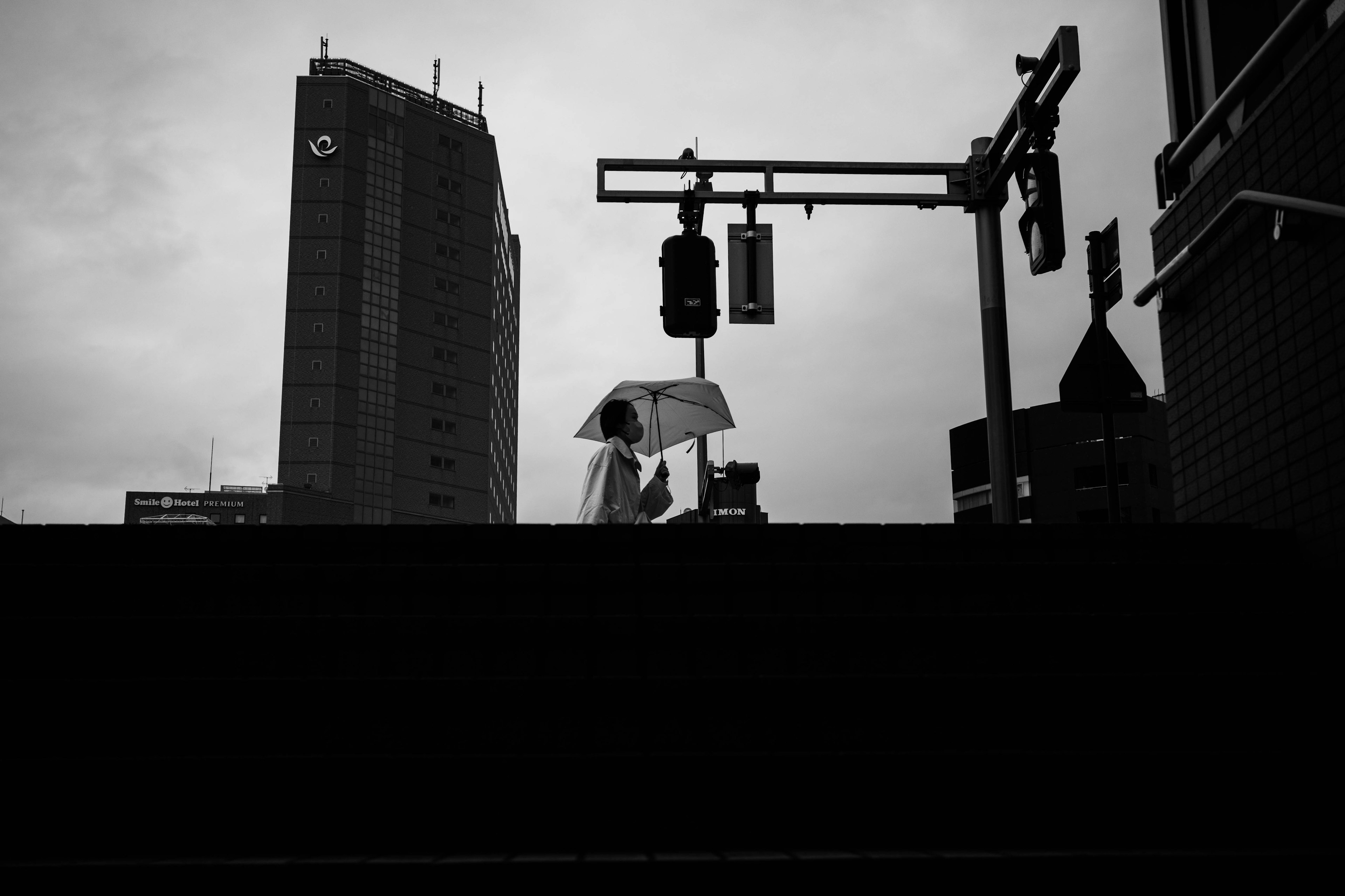 Eine Person mit einem Regenschirm, die in einer städtischen Landschaft in Schwarzweiß geht