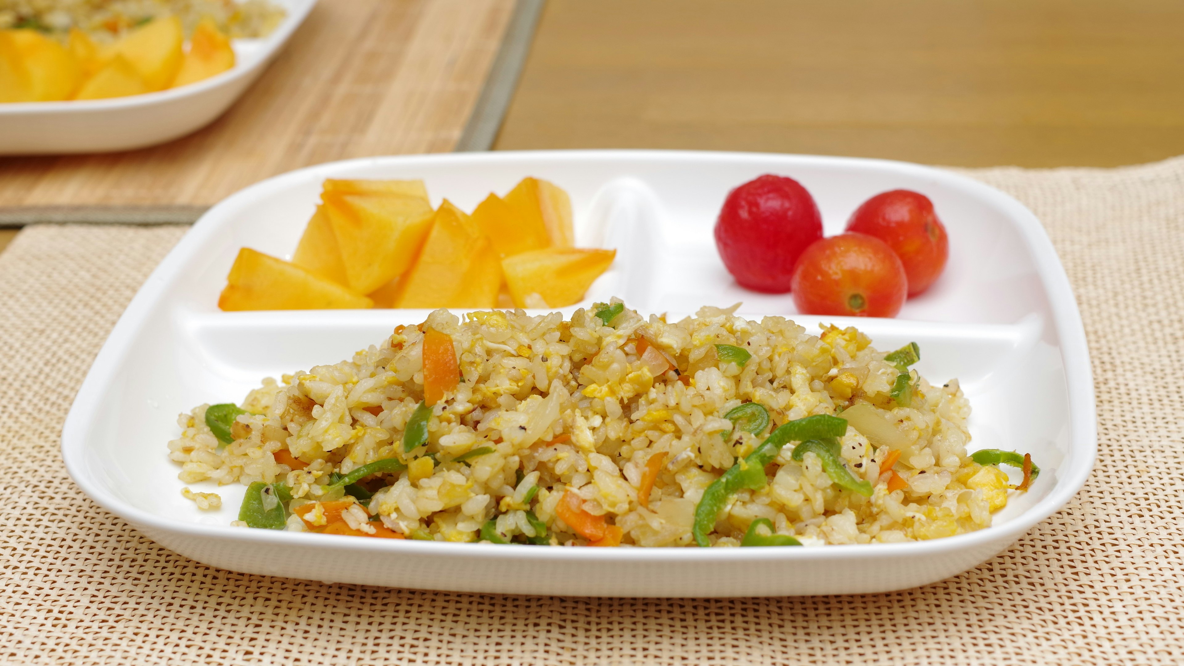 Nasi goreng dengan sayuran berwarna-warni dan piring buah