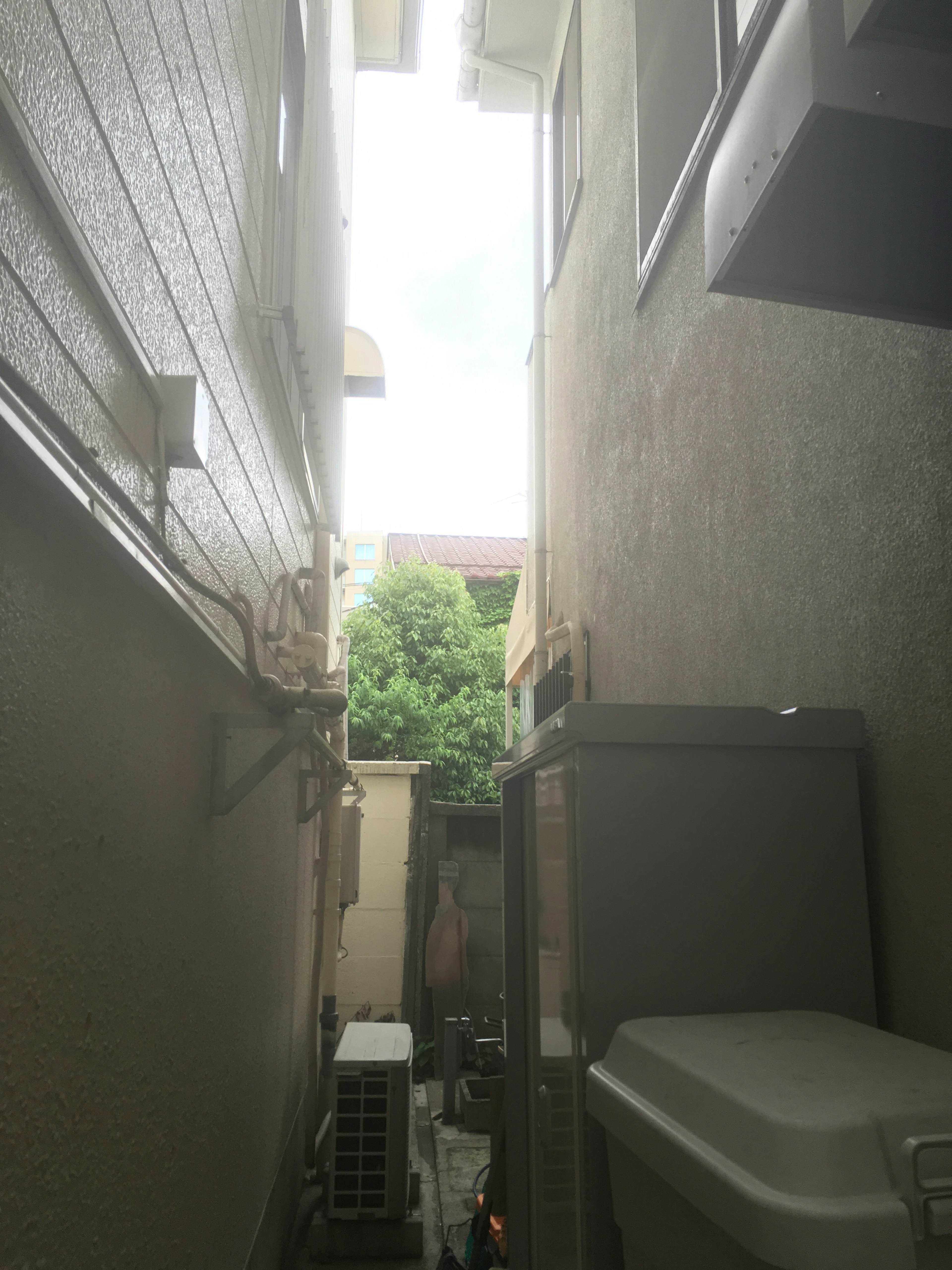 Narrow passage between buildings with greenery visible at the end