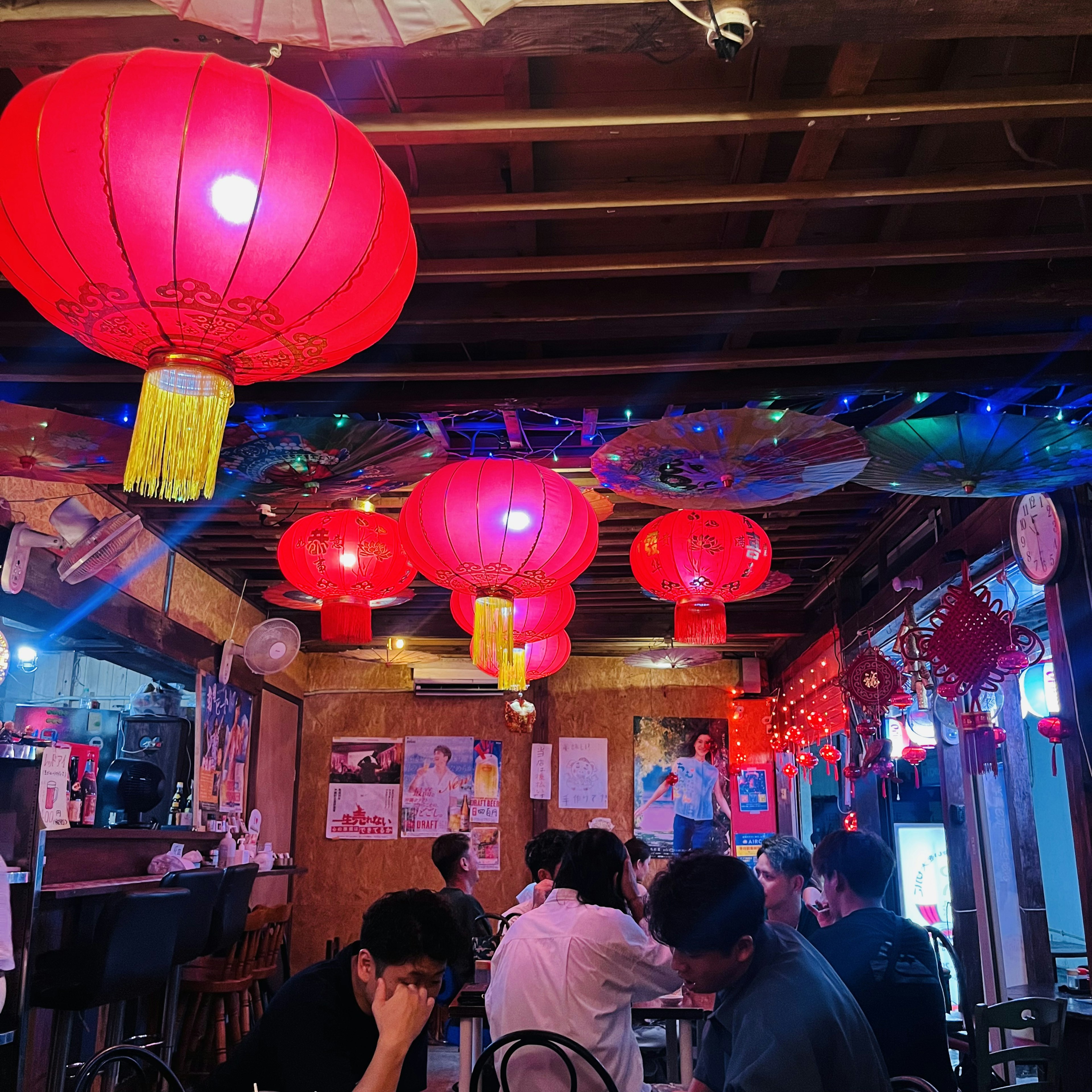 Interior of a lively restaurant with red lanterns hanging and people dining