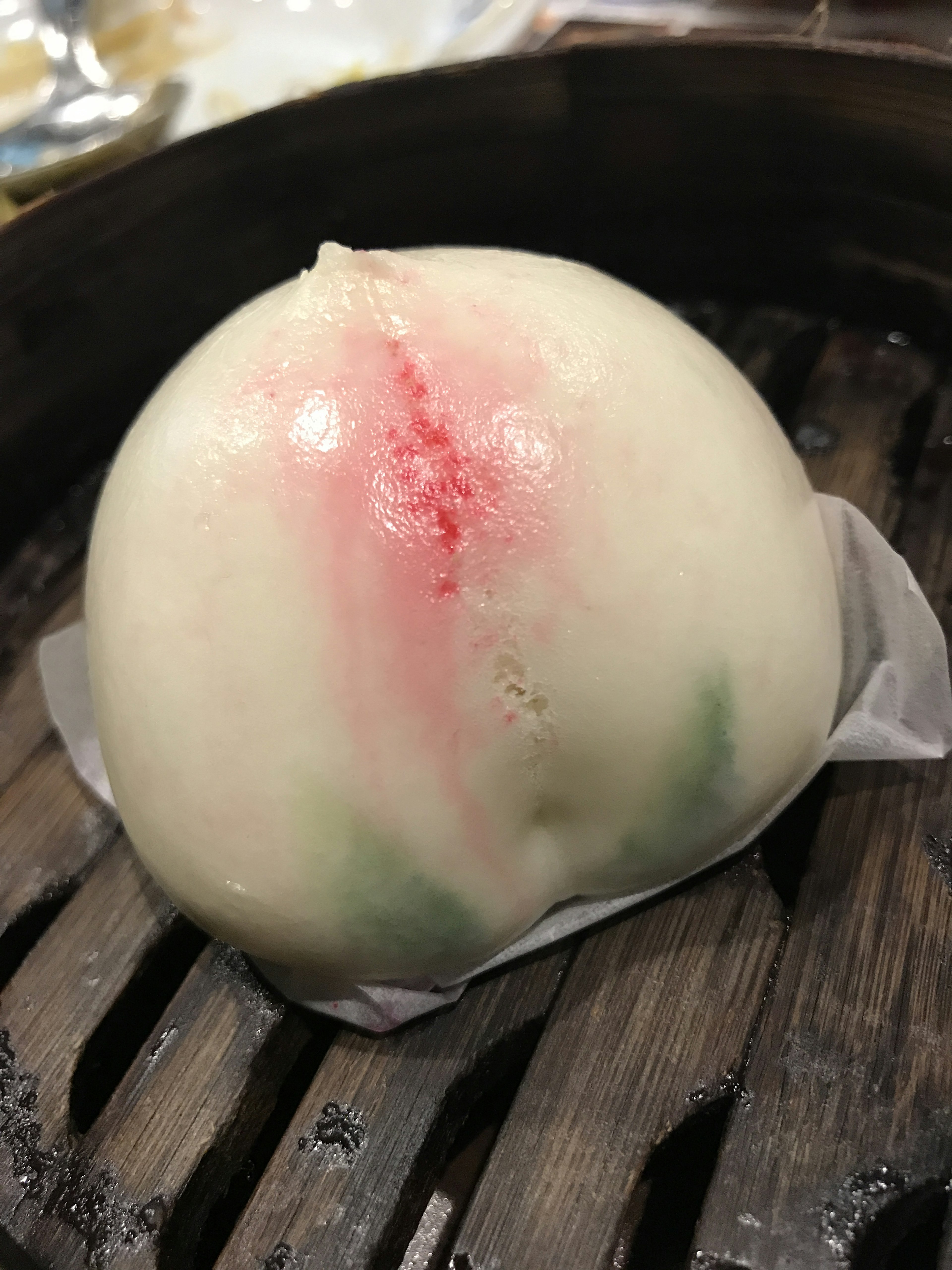 Steamed bun shaped like a peach with white skin and red green accents