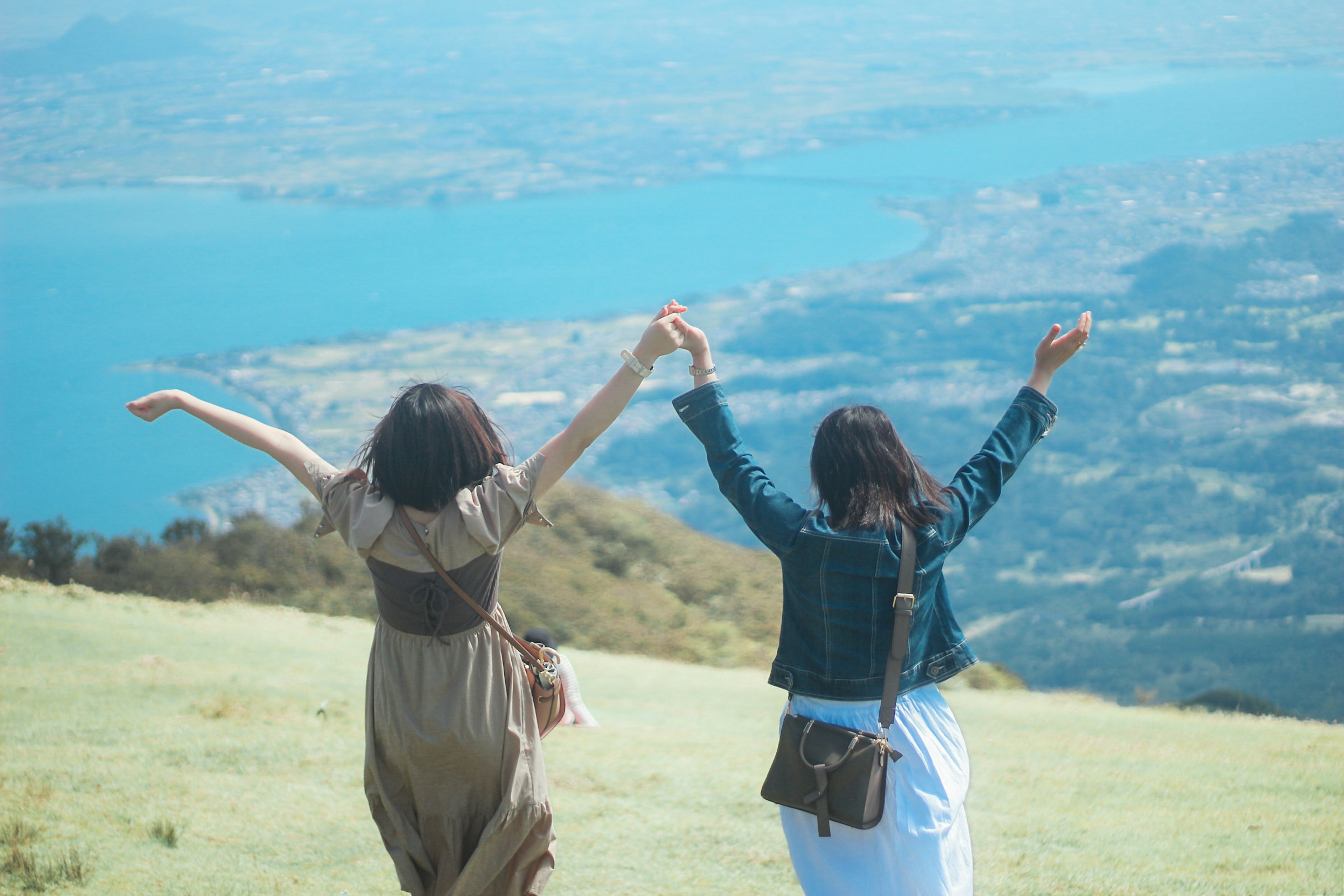 Two women holding hands expressing joy with a blue lake in the background