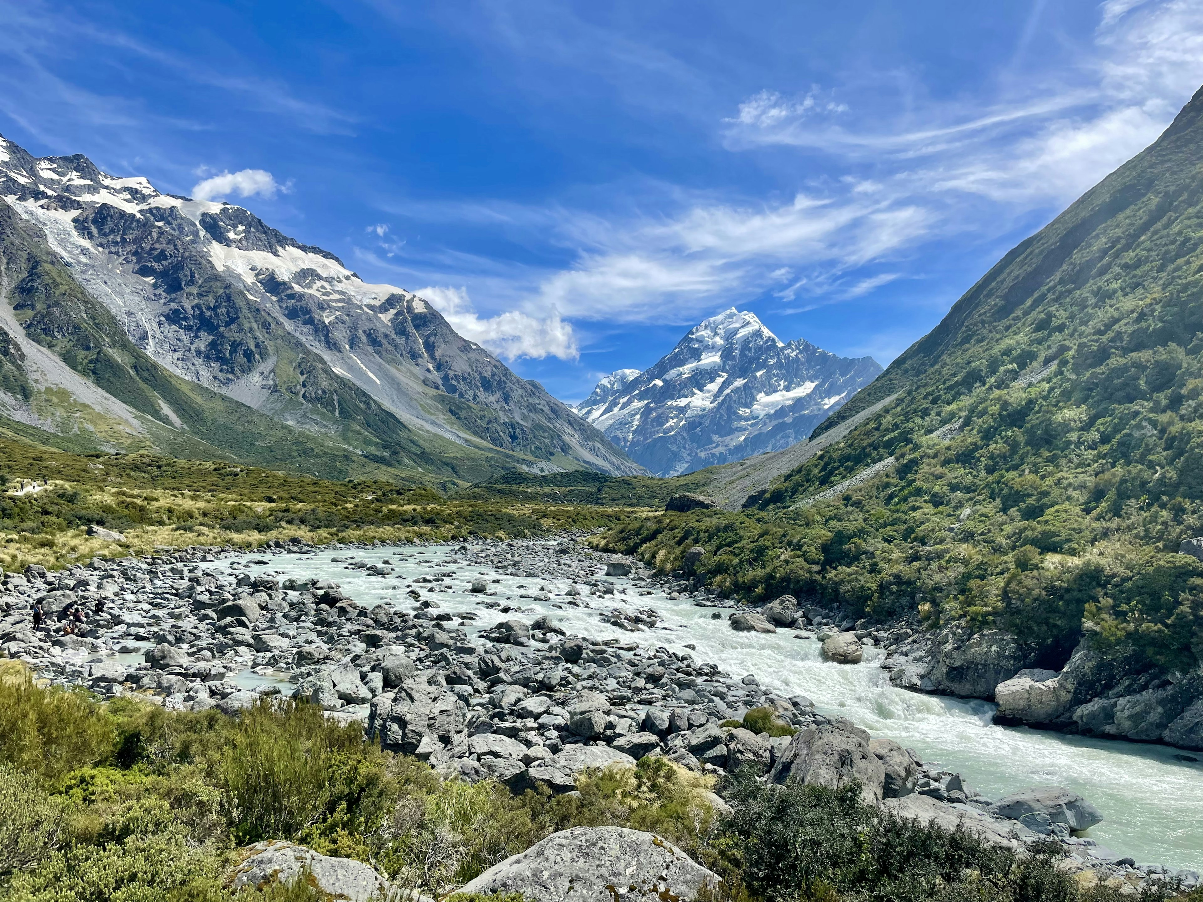 Scenic view of mountains and river under a blue sky with white clouds