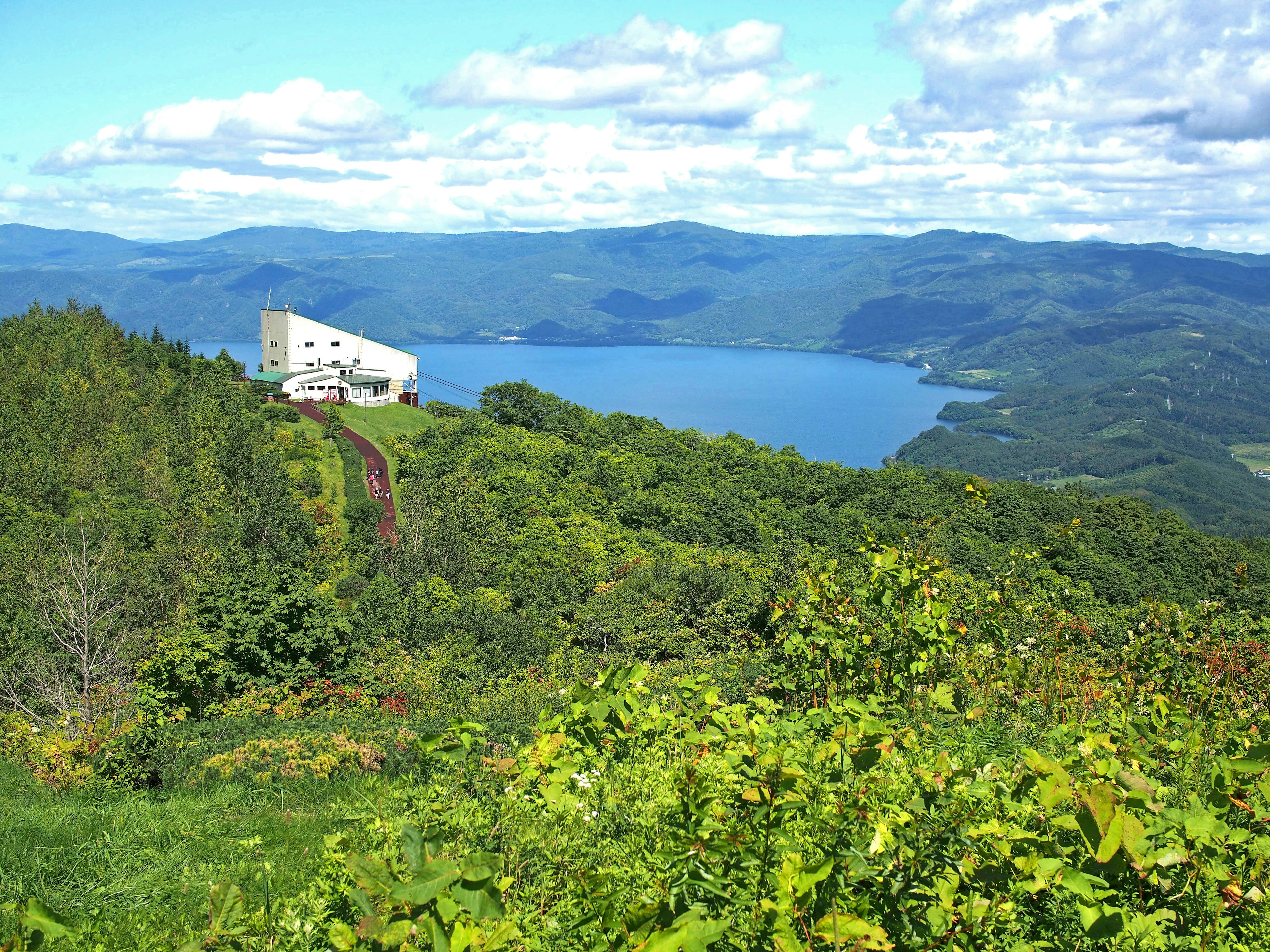 Un edificio blanco rodeado de un hermoso lago y montañas