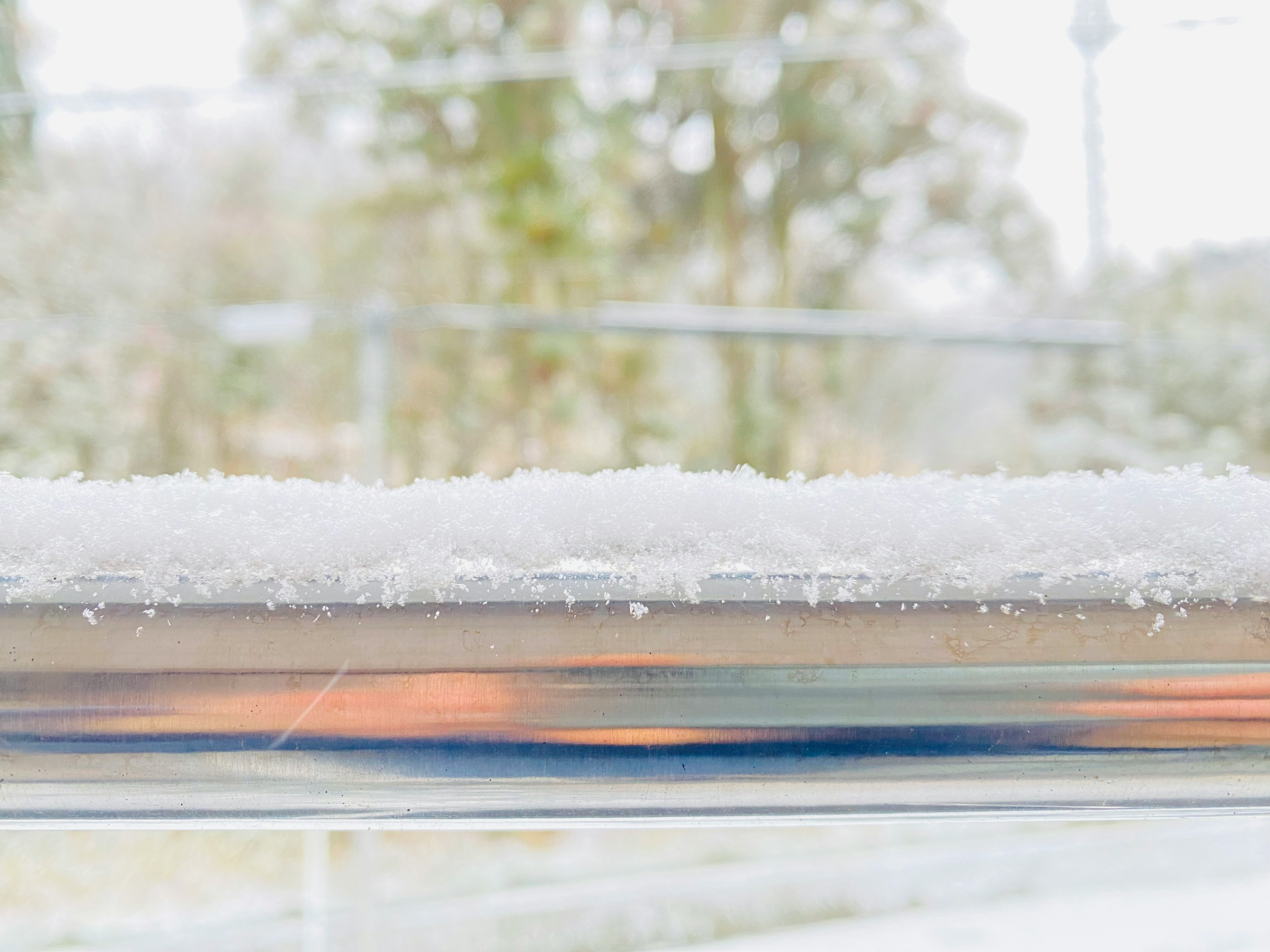 雪が積もった窓の縁とぼんやりした背景の木々