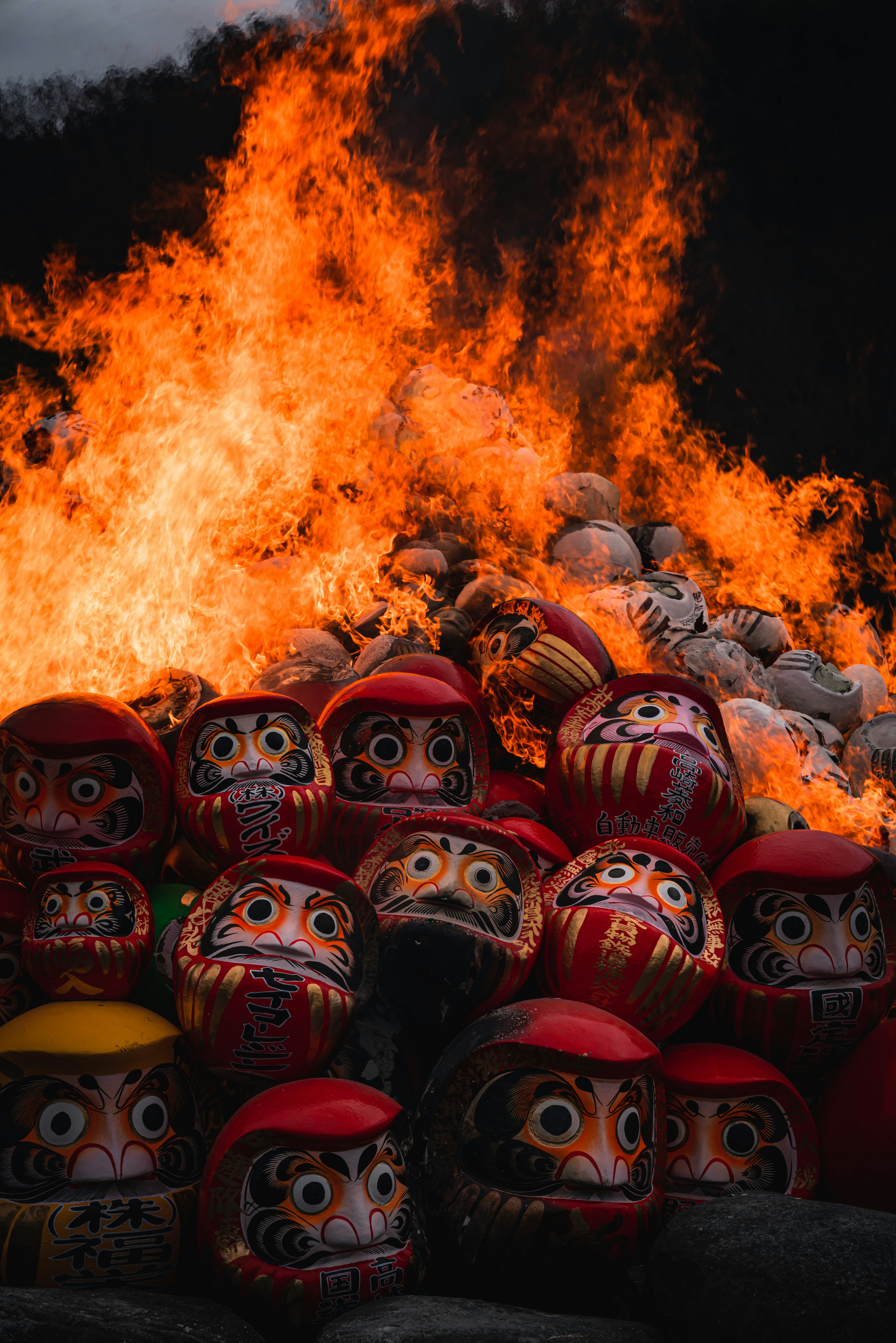 Eine Gruppe Daruma-Puppen umgeben von Flammen