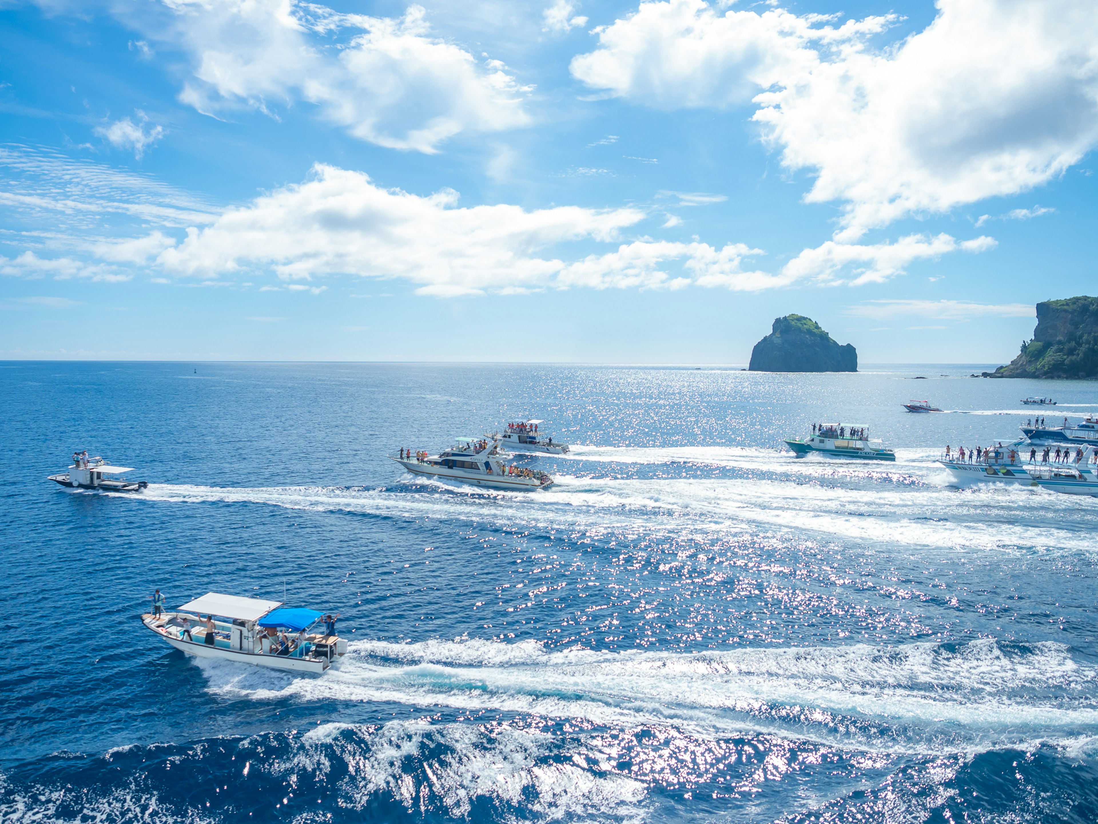 Multiple boats navigating on a blue sea under a bright sky